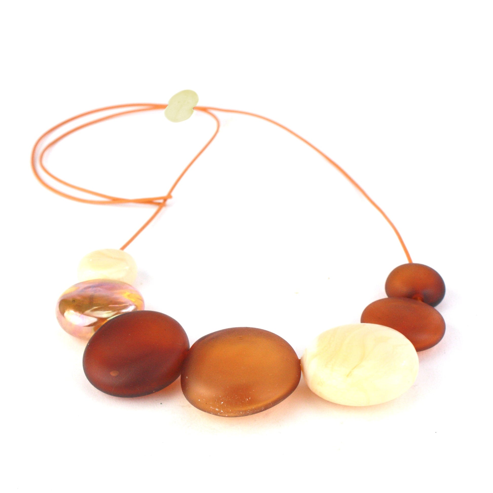 A handcrafted necklace featuring seven hollow hand-blown glass beads in amber, ivory, and gold hues, strung on adjustable leather for a versatile, elegant look.