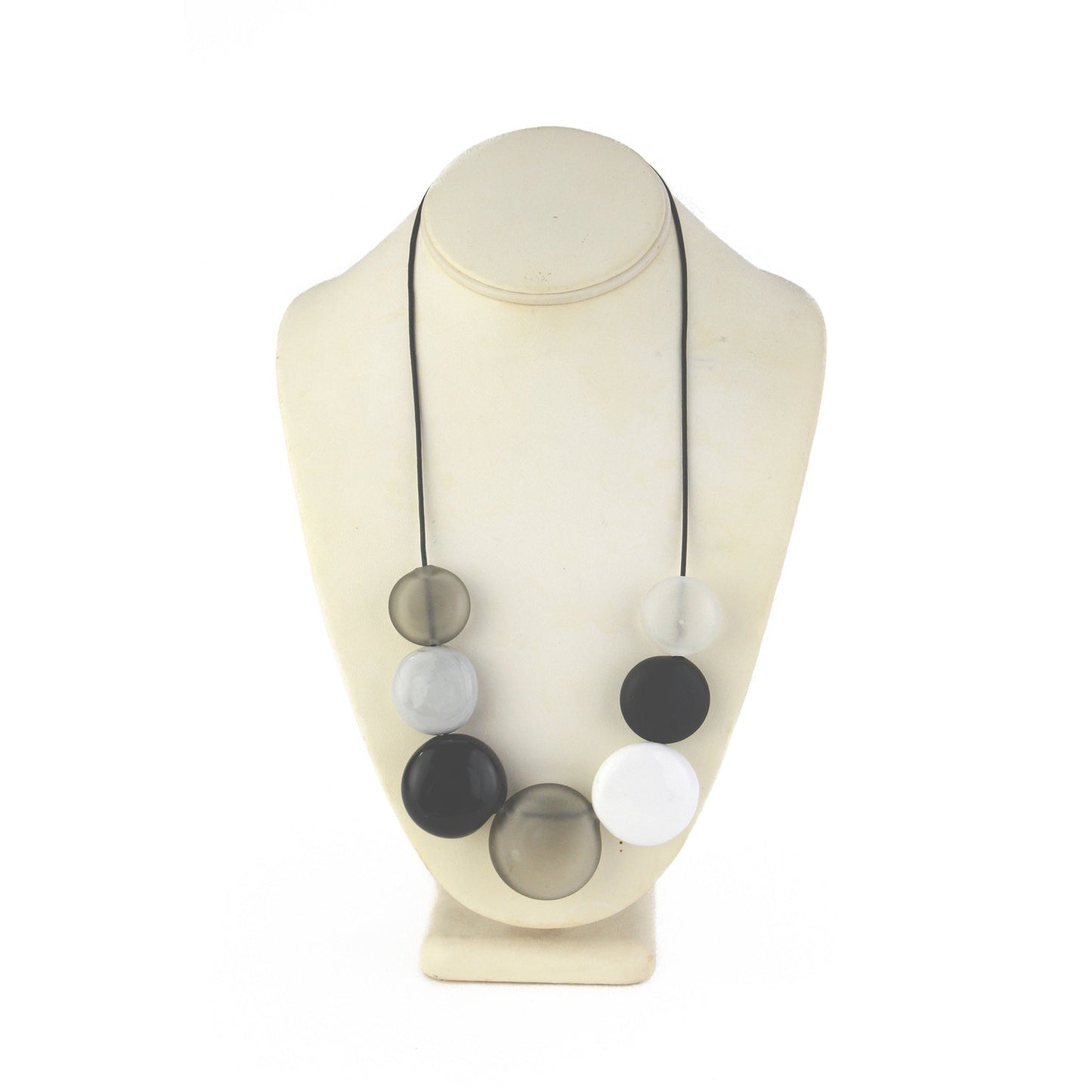 A monochromatic necklace featuring seven hollow, hand-blown glass beads in black, white, grey, and clear tones, strung on adjustable leather for versatile styling.