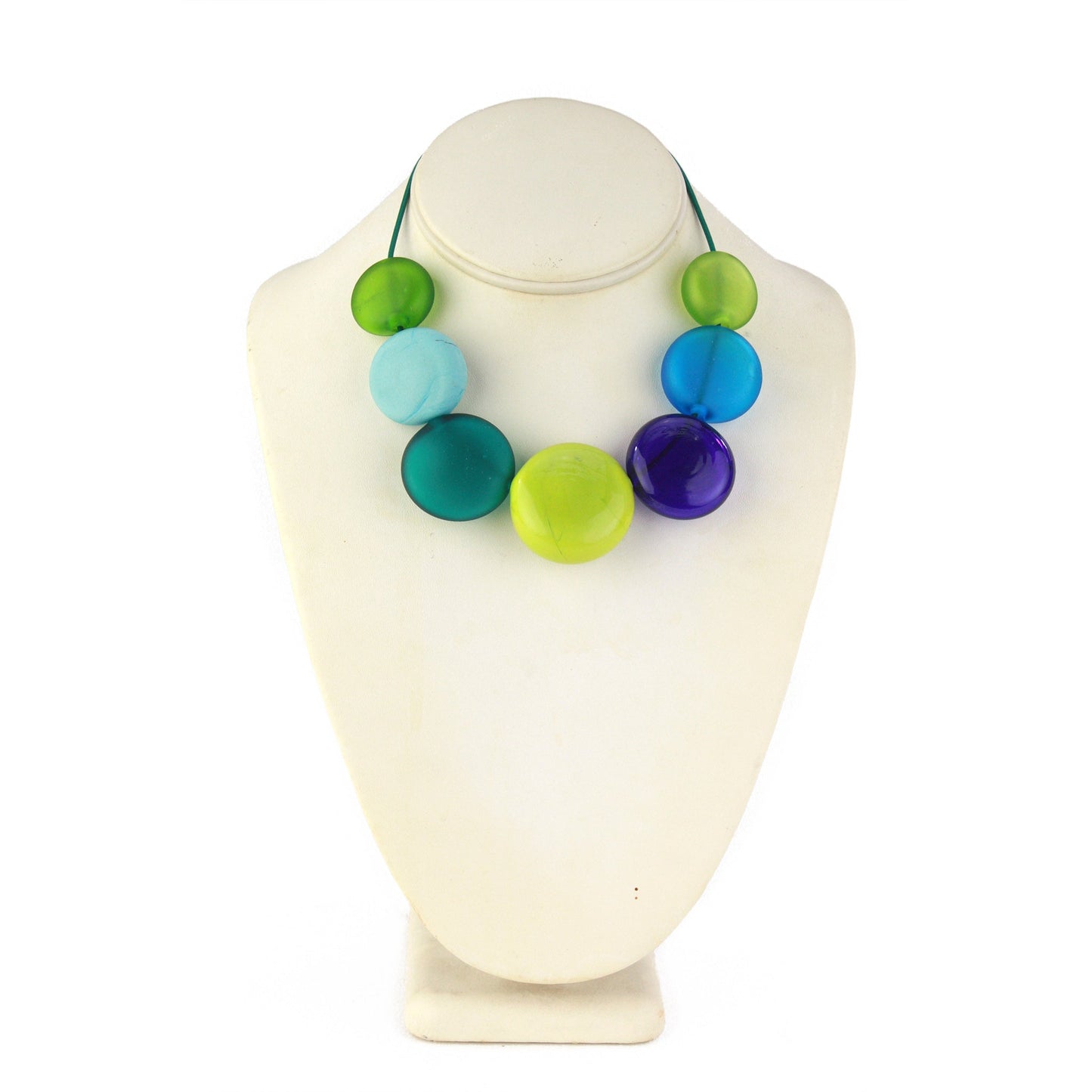 A vibrant necklace featuring seven hollow, hand-blown glass beads in shades of blue, teal, and green, strung on adjustable leather for versatile styling options.