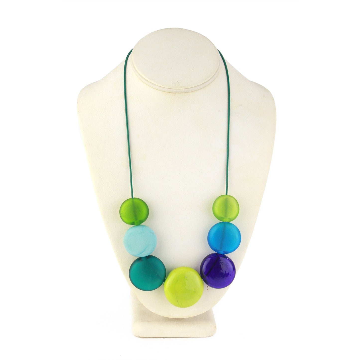 A vibrant necklace featuring seven hollow, hand-blown glass beads in shades of blue, teal, and green, strung on adjustable leather for versatile styling options.