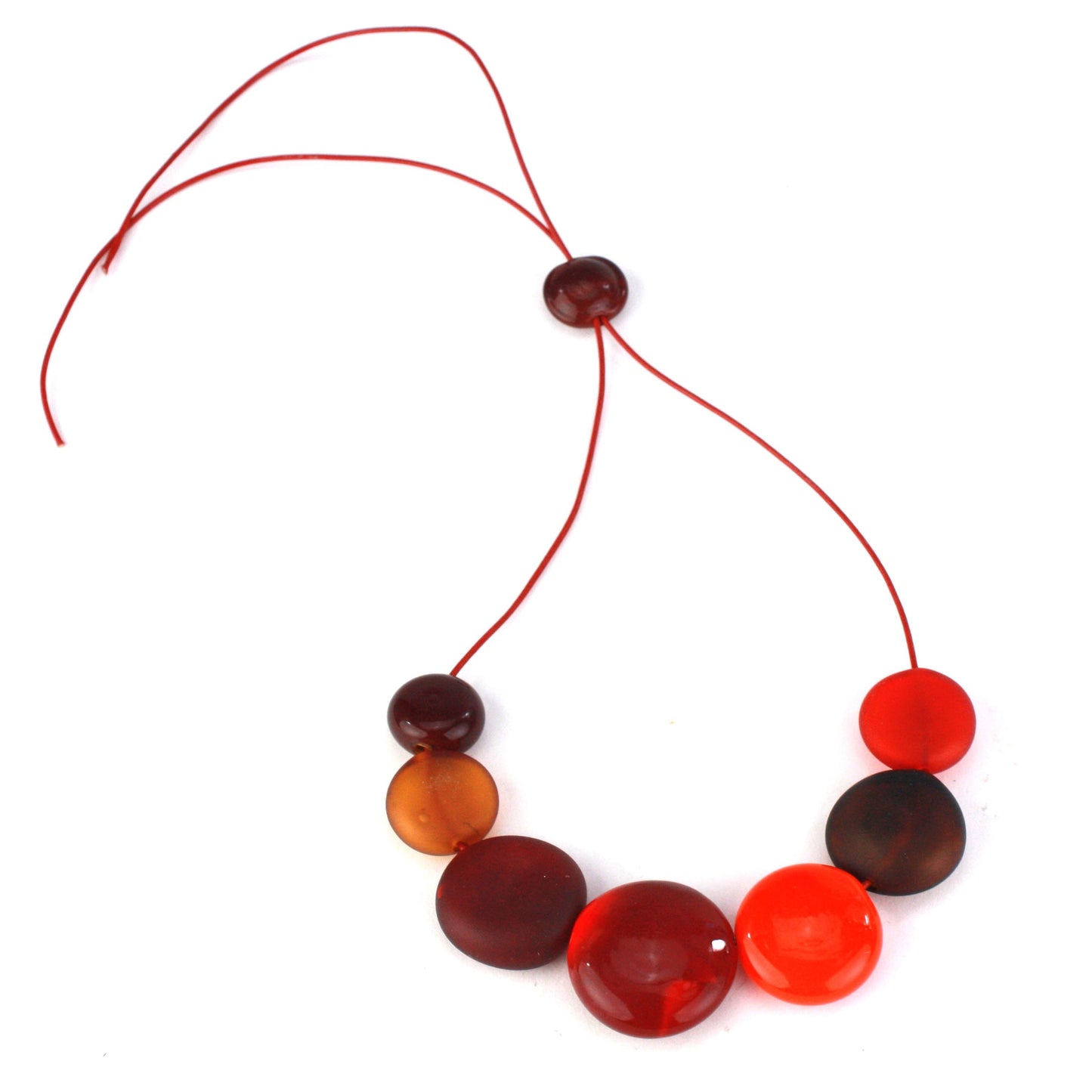 A striking necklace featuring seven hollow, hand-blown glass beads in warm shades of red, orange, and amber, strung on adjustable leather for versatile wear.
