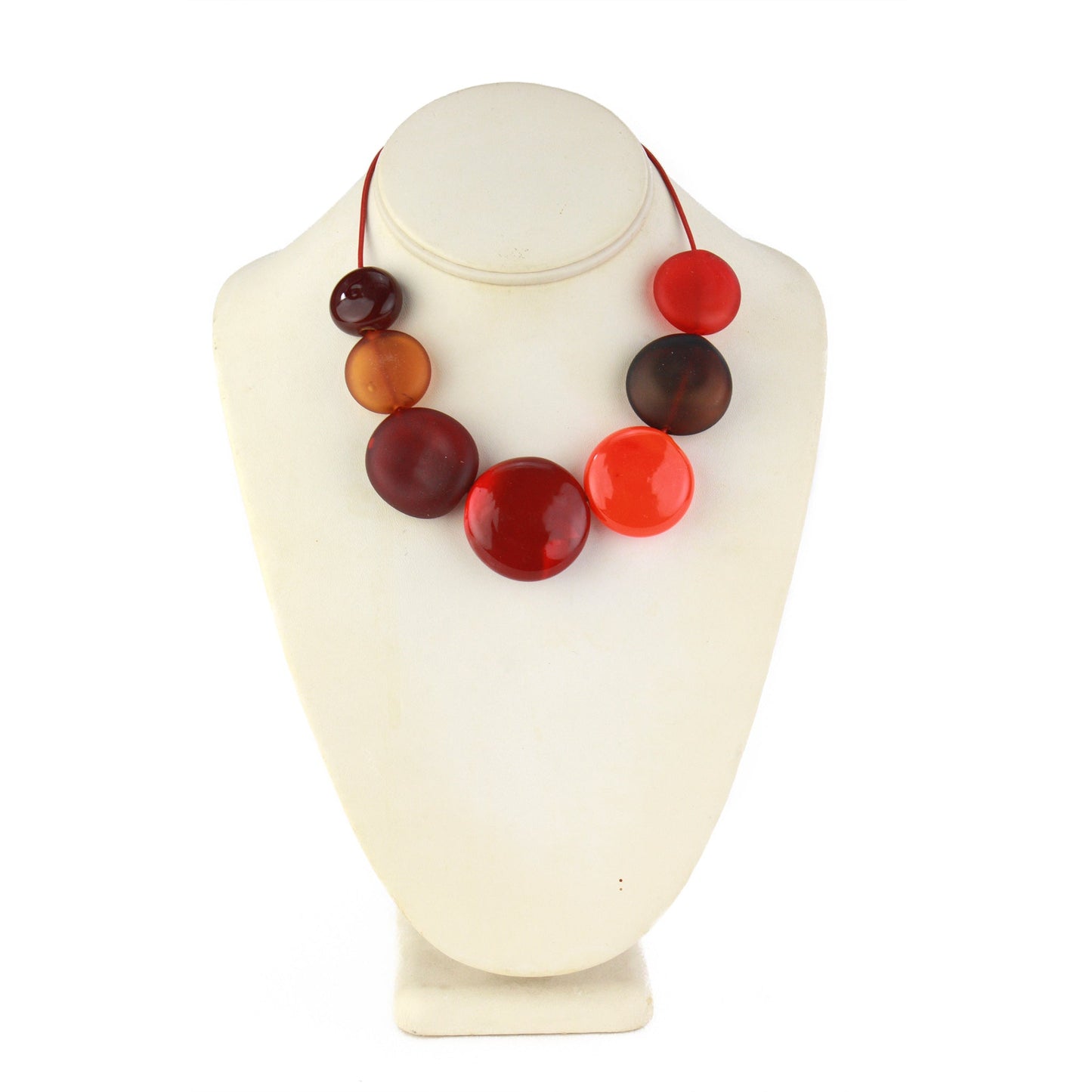 A striking necklace featuring seven hollow, hand-blown glass beads in warm shades of red, orange, and amber, strung on adjustable leather for versatile wear.
