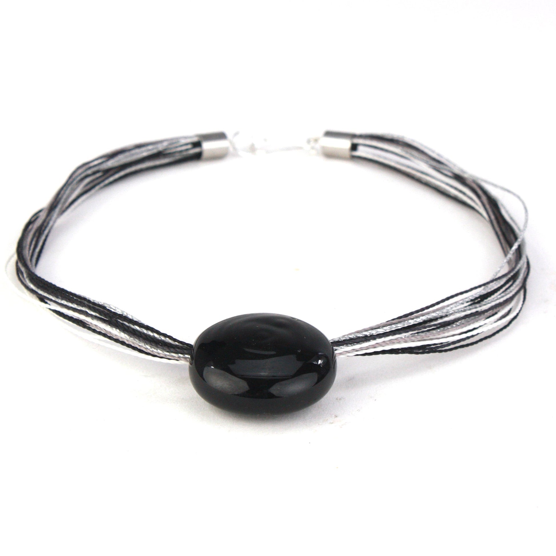 A sleek necklace featuring a hand-blown black glass focal bead strung on multi-strand waxed cord in black and silver tones. Finished with a sterling silver hook-and-loop clasp, this elegant piece offers a modern and sophisticated look.