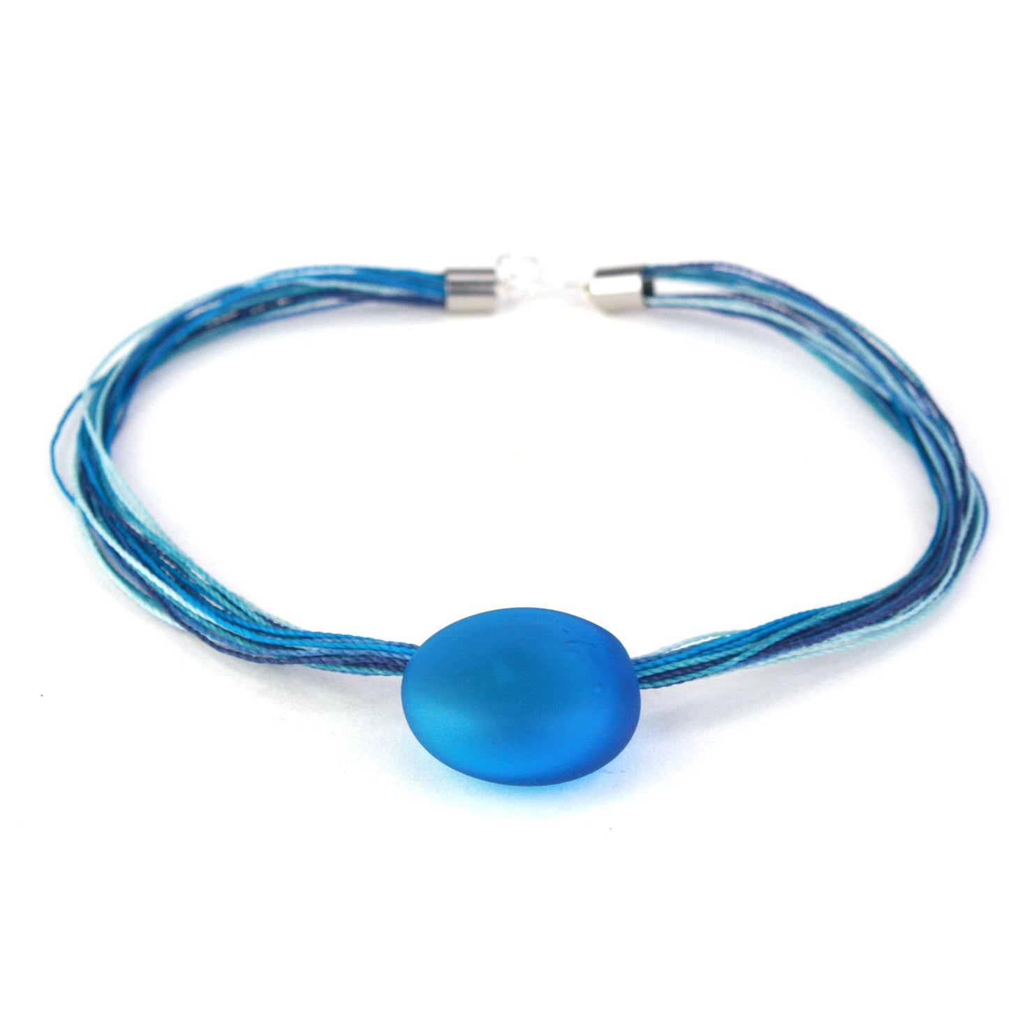 A vibrant necklace featuring a hand-blown blue glass focal bead strung on multi-strand waxed cord in coordinating blue tones. Finished with a sterling silver hook-and-loop clasp, this elegant piece adds a bold pop of color to any outfit.