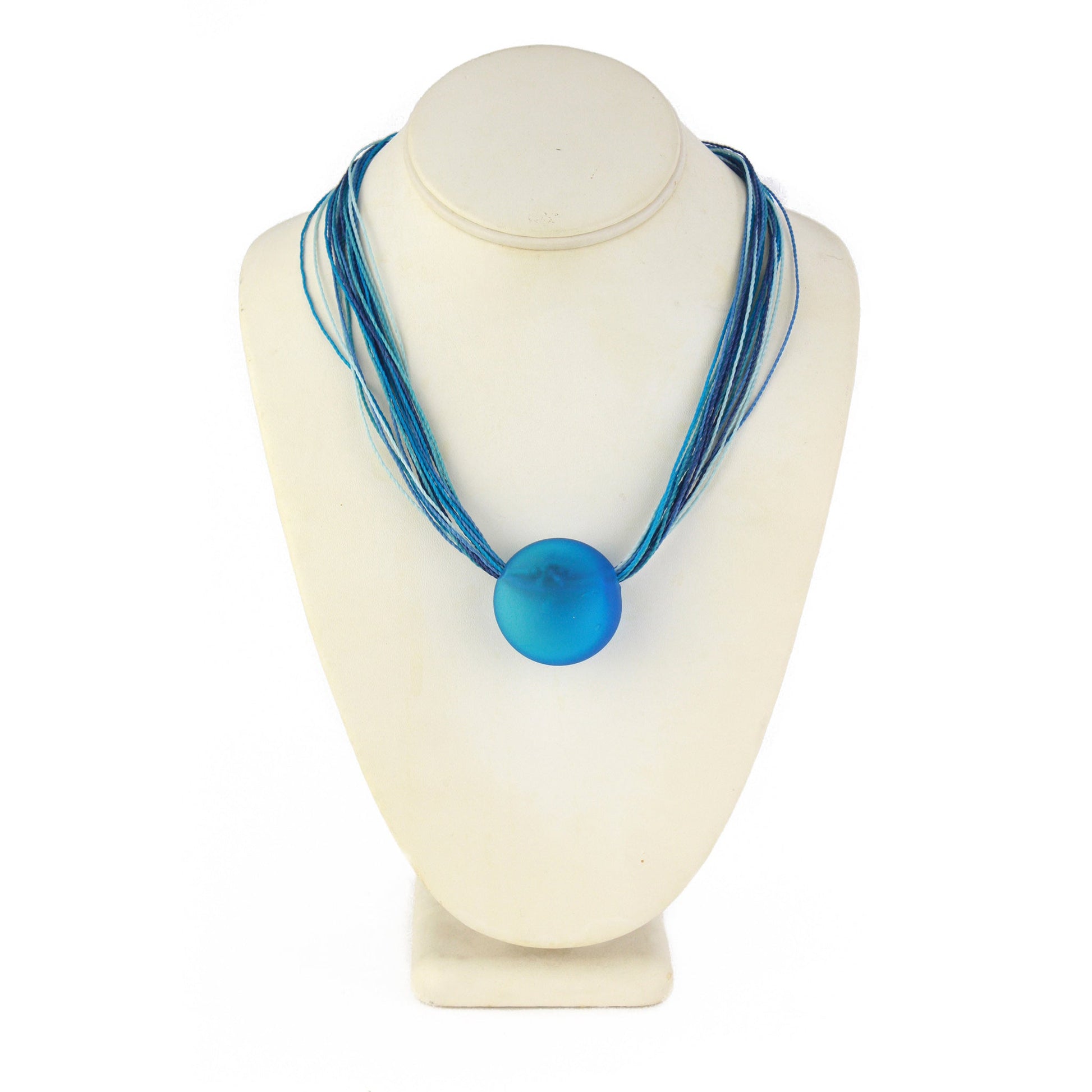 A vibrant necklace featuring a hand-blown blue glass focal bead strung on multi-strand waxed cord in coordinating blue tones. Finished with a sterling silver hook-and-loop clasp, this elegant piece adds a bold pop of color to any outfit.