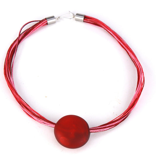 A romantic necklace featuring a hand-blown red glass focal bead strung on multi-strand waxed cord in rich shades of red and pink. Finished with a sterling silver hook-and-loop clasp, this piece adds a bold yet elegant touch to any outfit.