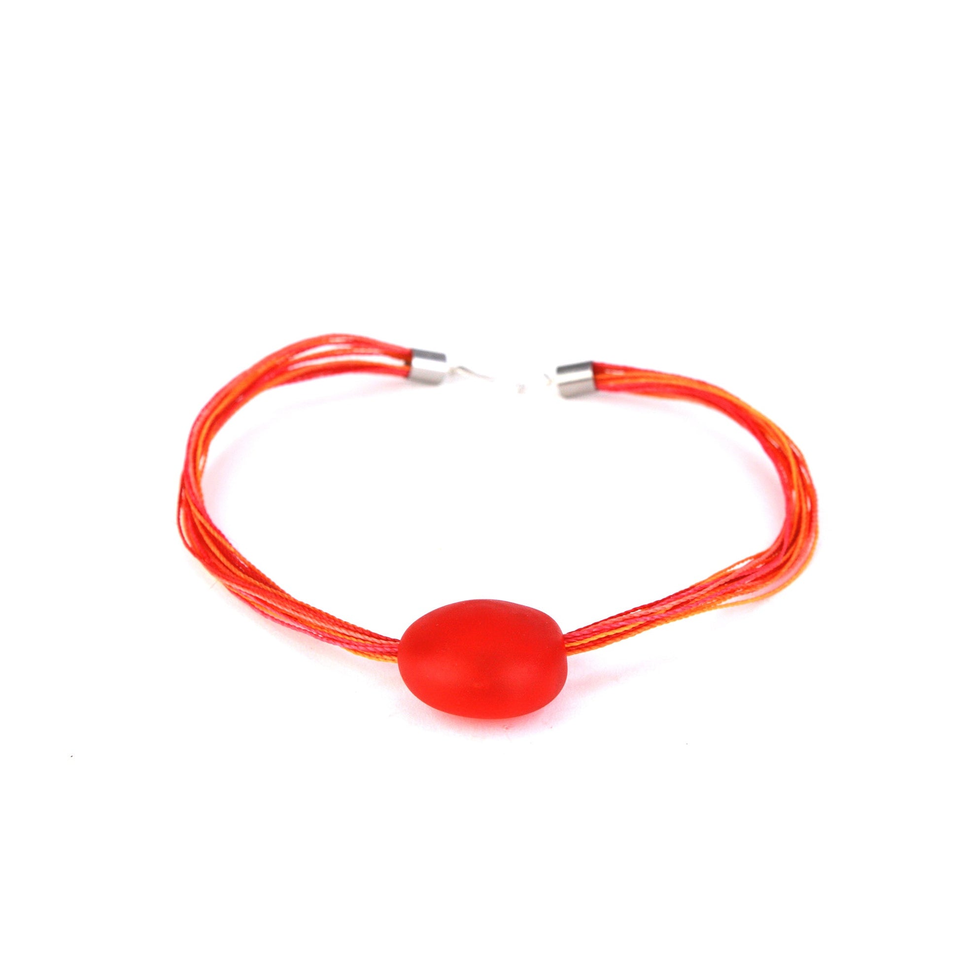 A vibrant necklace featuring a hand-blown orange glass focal bead strung on multi-strand waxed cord in warm orange and tangerine tones. Finished with a sterling silver hook-and-loop clasp, this piece adds a bold and colorful touch to any outfit.