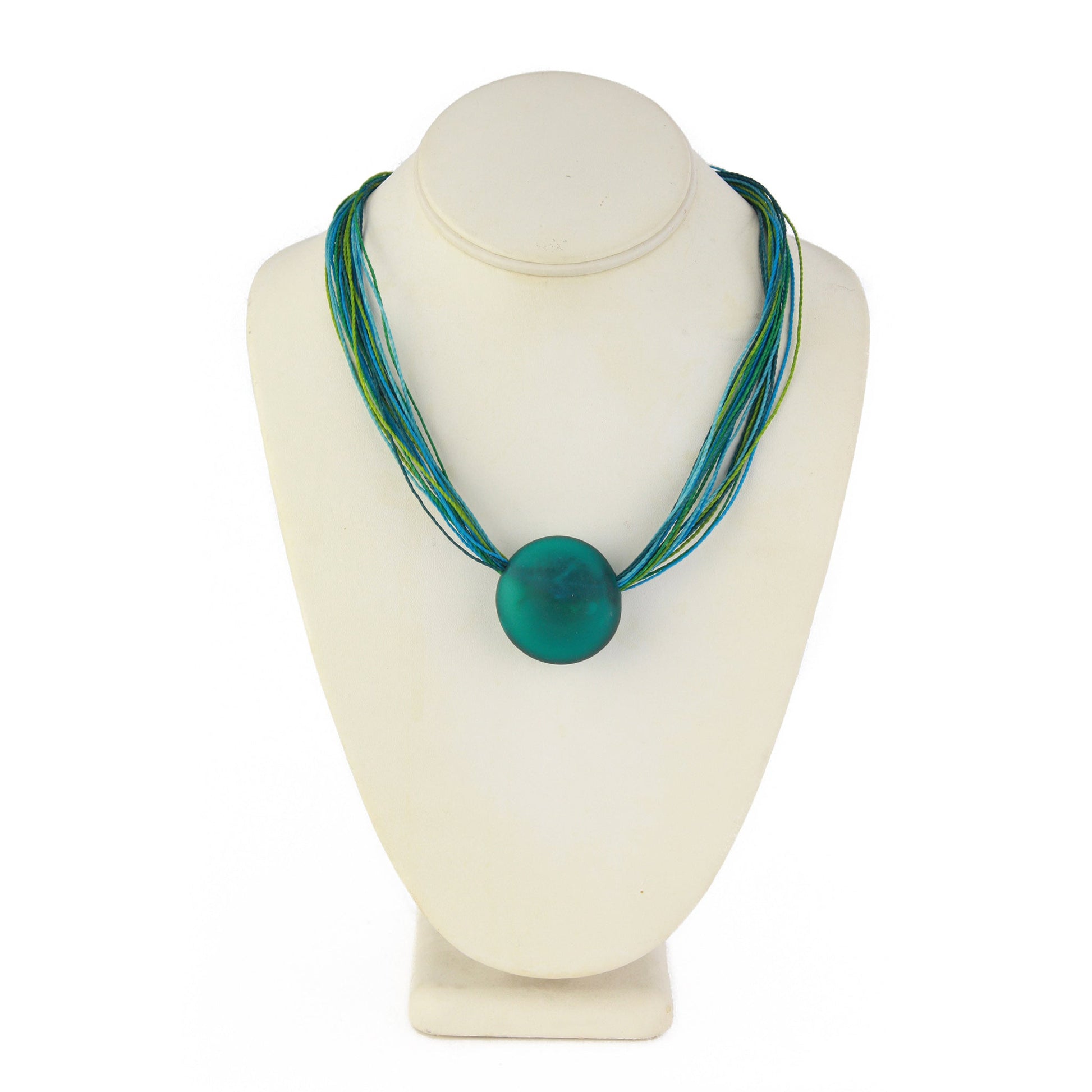 A vibrant necklace featuring a hand-blown teal glass focal bead strung on multi-strand waxed cord in shades of teal and aqua. Finished with a sterling silver hook-and-loop clasp, this piece offers a bold, ocean-inspired accent.