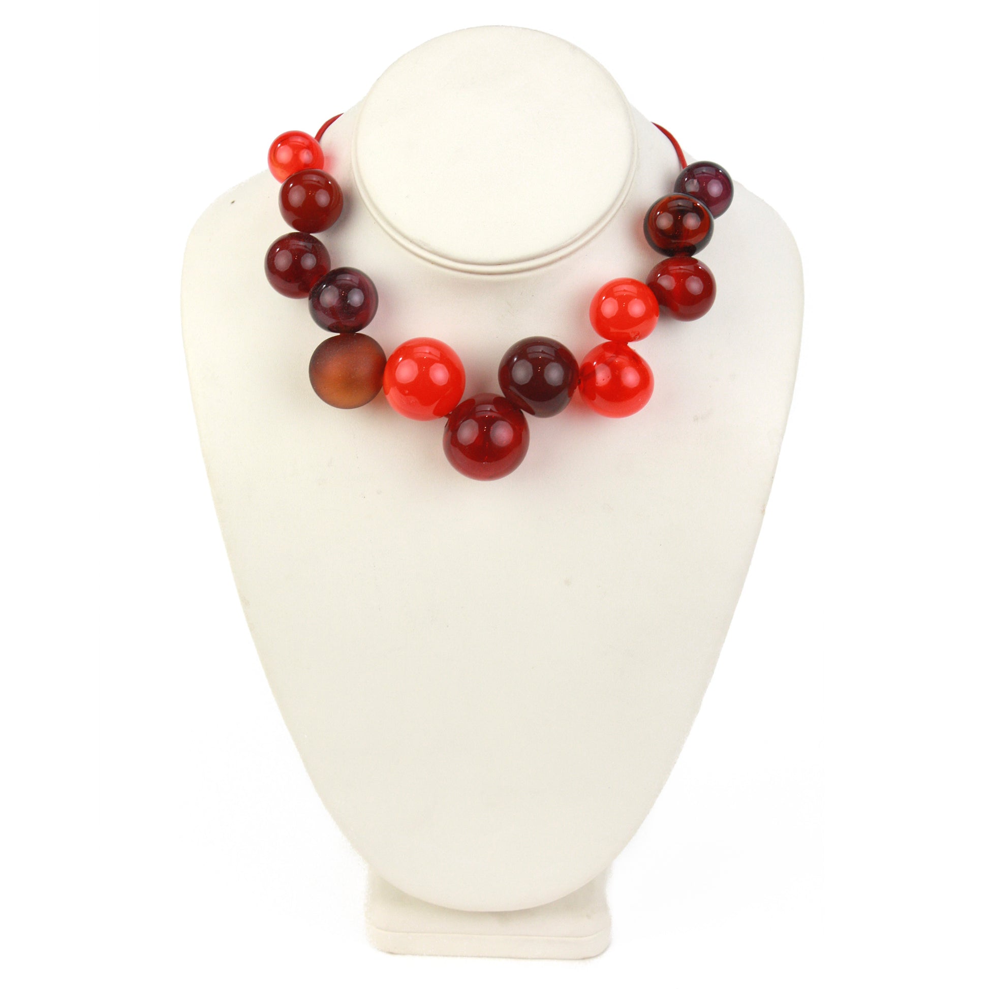 Offset Bolla Necklace featuring hand-blown glass beads in red, amber, and burgundy hues strung on red leather cord with a handcrafted adjustable slider bead.