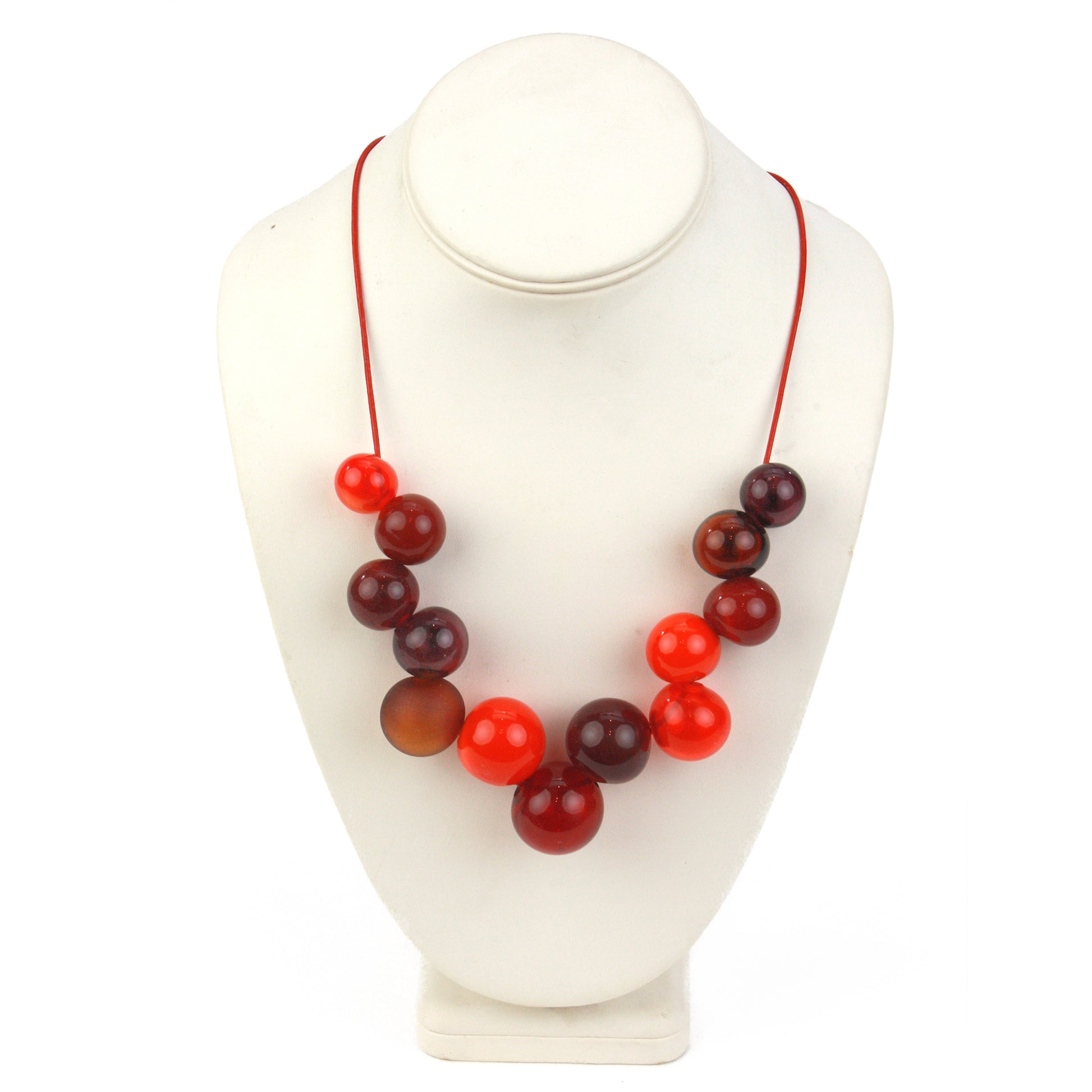 Offset Bolla Necklace featuring hand-blown glass beads in red, amber, and burgundy hues strung on red leather cord with a handcrafted adjustable slider bead.