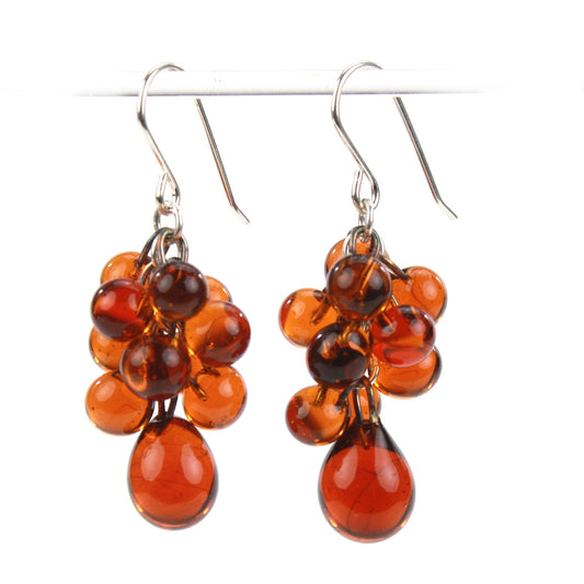 Amber Cluster Earrings featuring cascading handmade glass beads in rich amber hues, paired with sterling silver ear wires for a bold, sophisticated look.