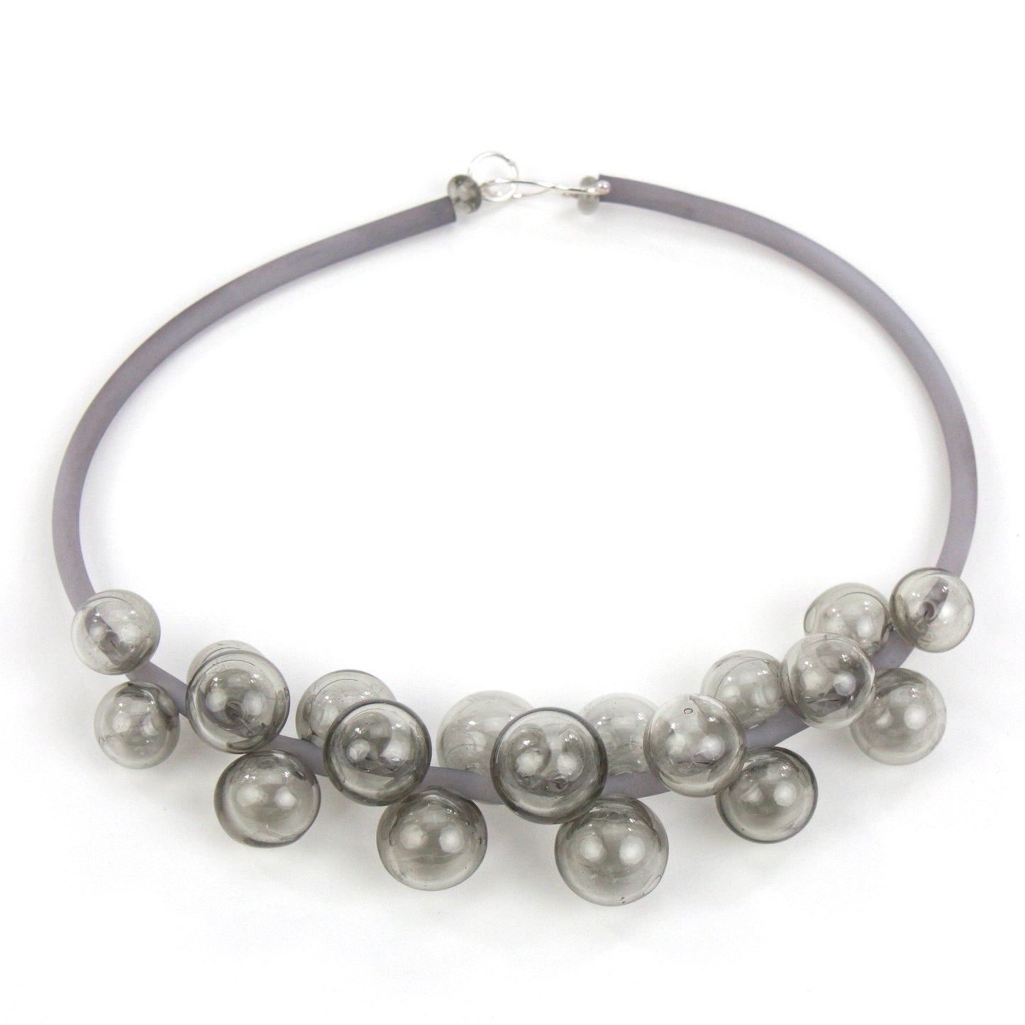 A smoky gray Chroma necklace featuring clustered handblown glass beads strung on steel wire and threaded through a hand-dyed silicone cord with a sterling silver clasp.