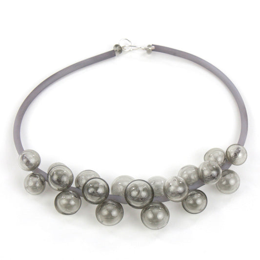 A smoky gray Chroma necklace featuring clustered handblown glass beads strung on steel wire and threaded through a hand-dyed silicone cord with a sterling silver clasp.