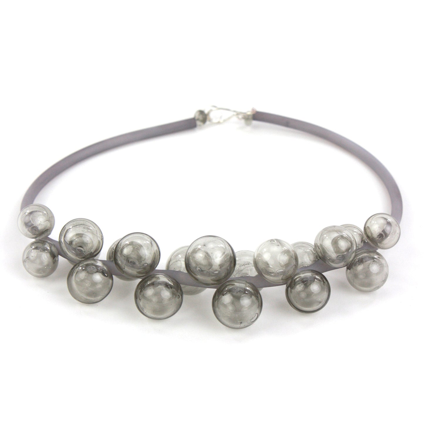 A smoky gray Chroma necklace featuring clustered handblown glass beads strung on steel wire and threaded through a hand-dyed silicone cord with a sterling silver clasp.