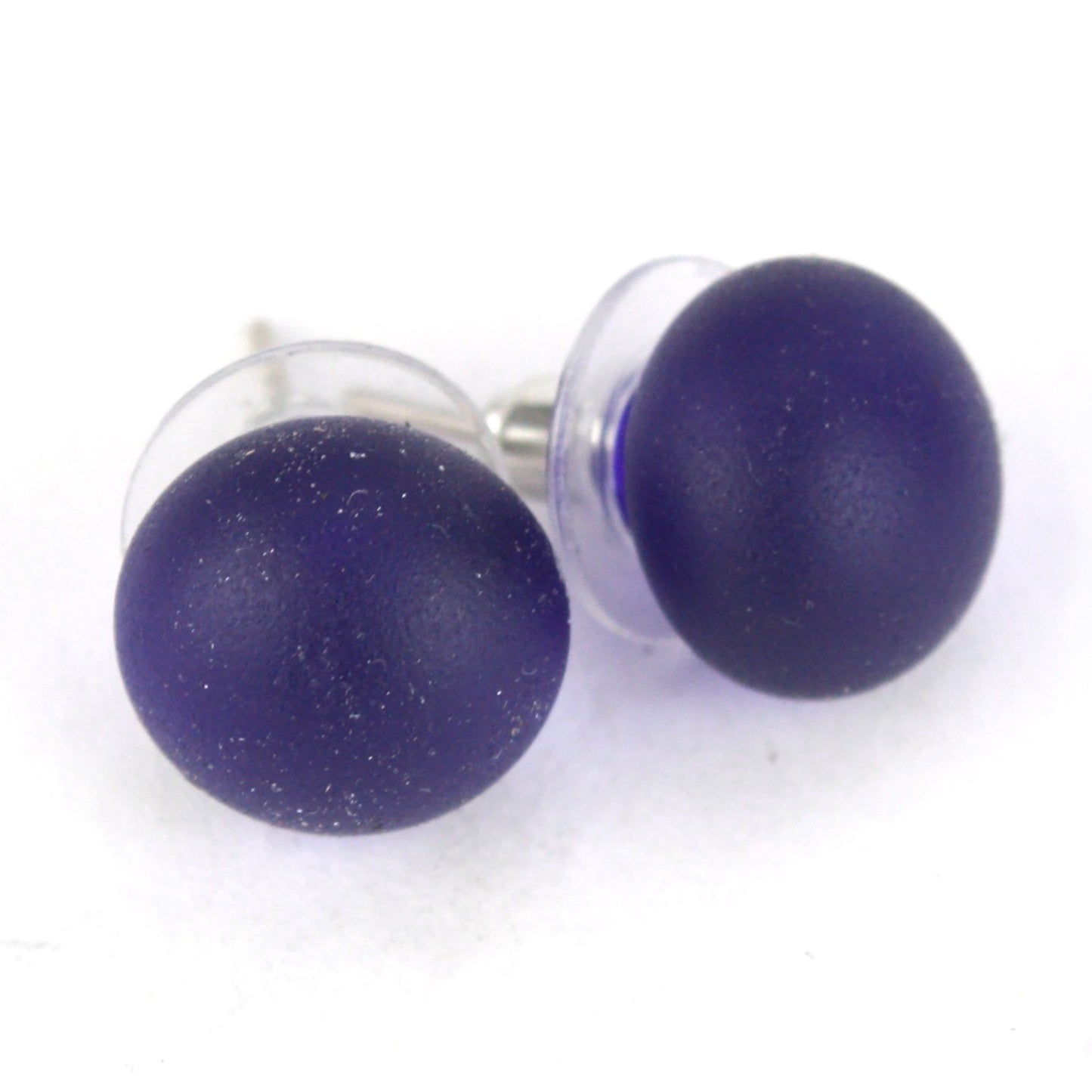 Pair of sandblasted cobalt blue glass stud earrings with frosted matte finish and sterling silver posts, paired with clear earring backs.