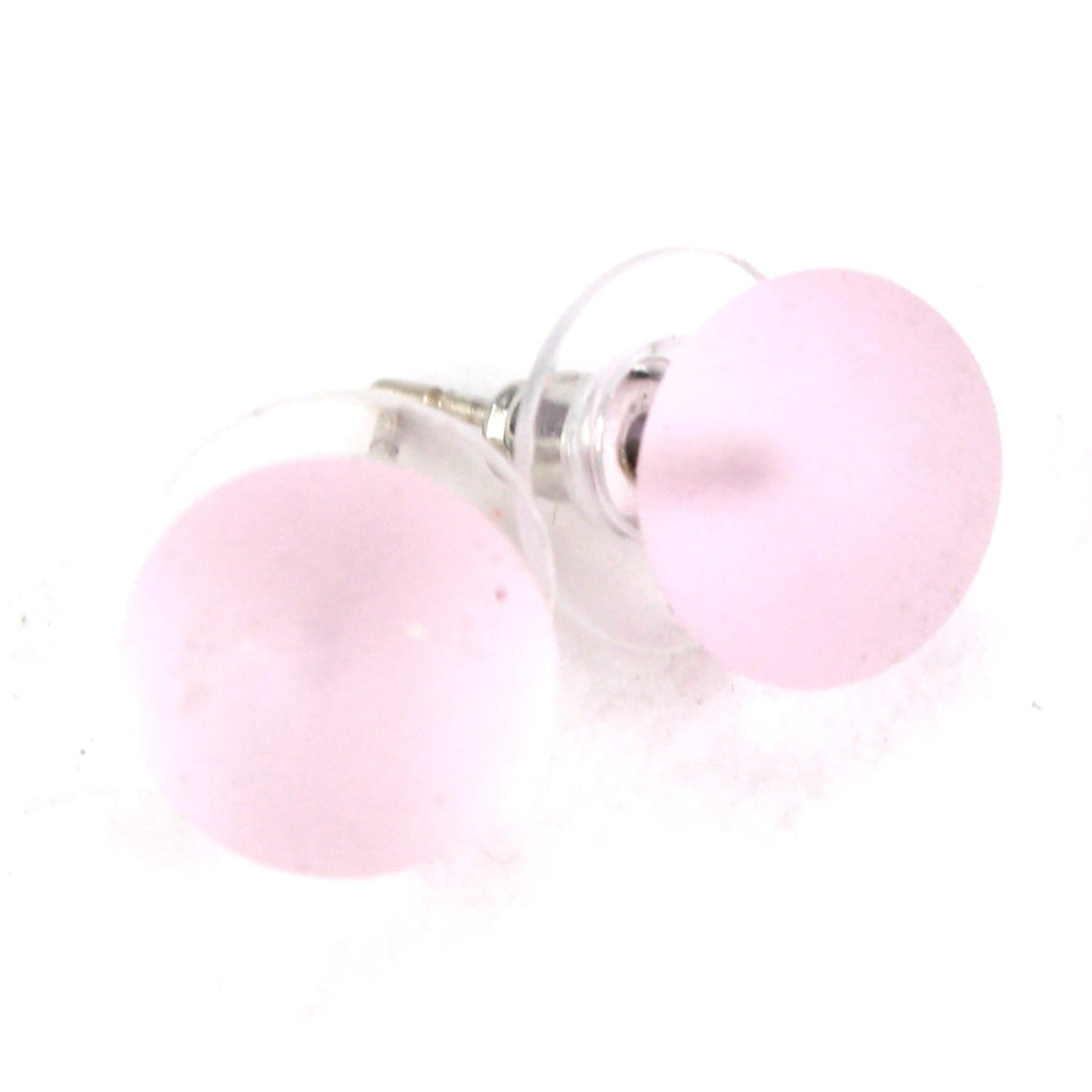 Pair of small frosted pink glass stud earrings with matte finish and sterling silver posts, paired with clear earring backs.