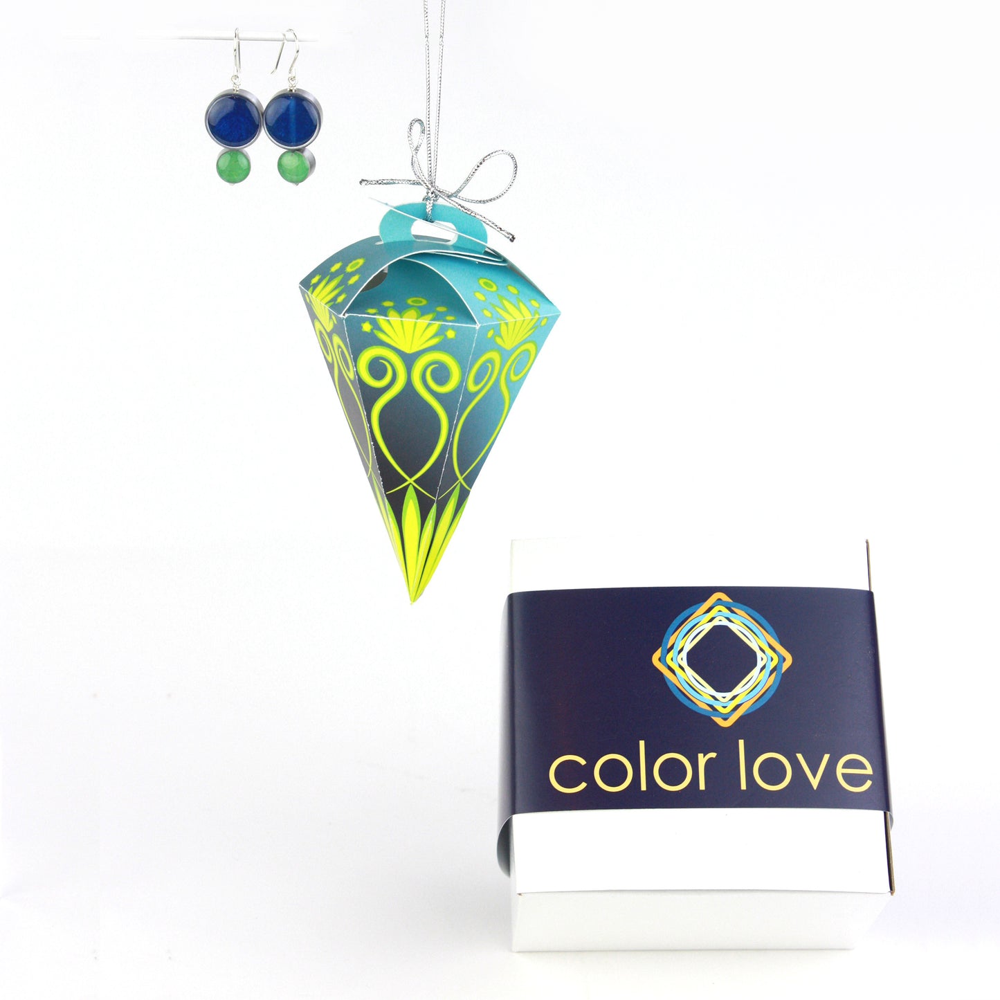 A pair of double-circle earrings in blue and green displayed alongside a blue and green festive ornament box, designed for hanging, and a coordinating Color Love-branded gift box.