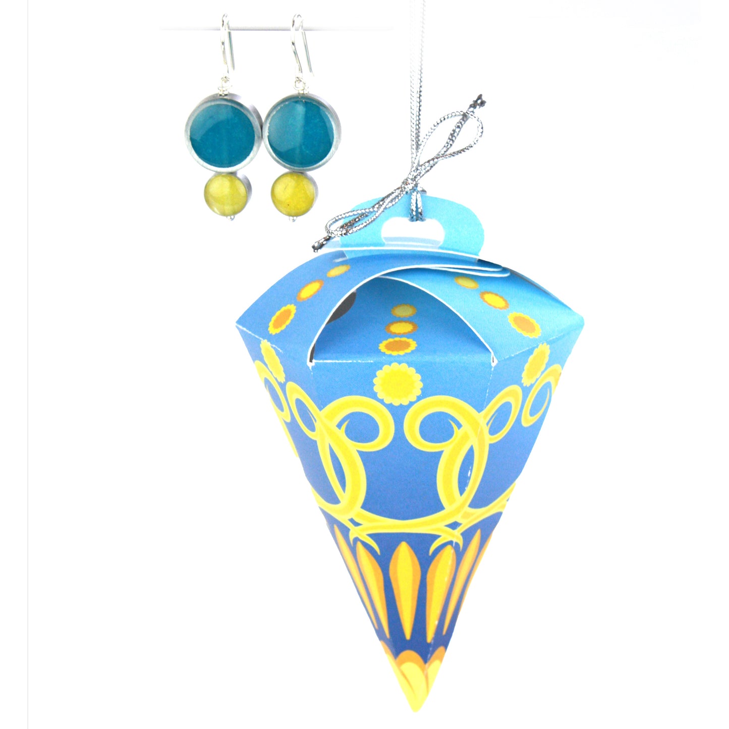 A pair of double-circle earrings in teal and yellow displayed alongside a blue and yellow festive ornament box, designed for hanging on a tree.