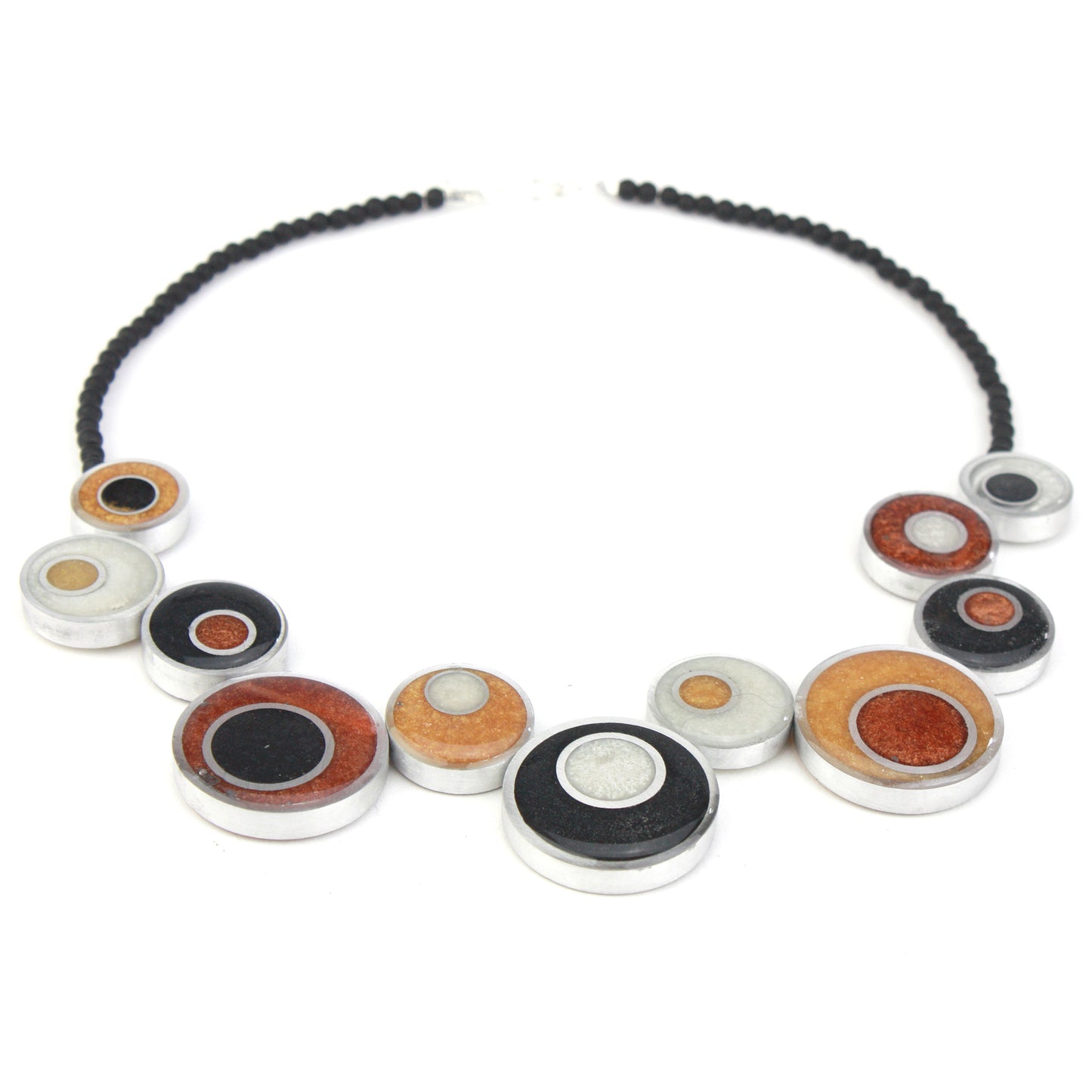 A handcrafted offset necklace featuring eco-resin and salvaged aluminum beads in black, white, copper, and gold tones, accented with glass beads and a silver clasp.