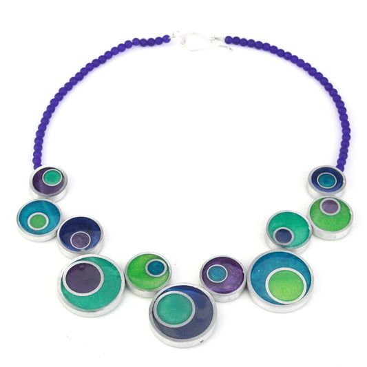 The Resinique Offset Necklace in vibrant blues and greens brings a refreshing, modern twist to sustainable design. Crafted from eco-resin and salvaged aluminum, its playful offset circular beads are strung on bold purple glass beads, creating a statement piece that captures the essence of nature’s vivid colors.
Handcrafted with eco-resin and salvaged aluminum for a sustainable, artistic design.
Features soothing blues and greens inspired by nature, accented with soft purple tones.
Offset circular arrangeme