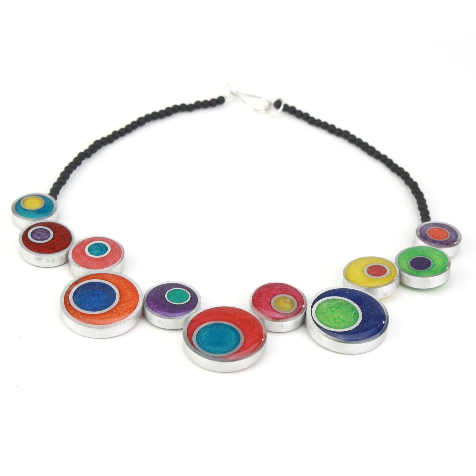 A colorful handcrafted offset necklace with eco-resin and salvaged aluminum beads in red, blue, yellow, green, and purple, finished with black glass beads.