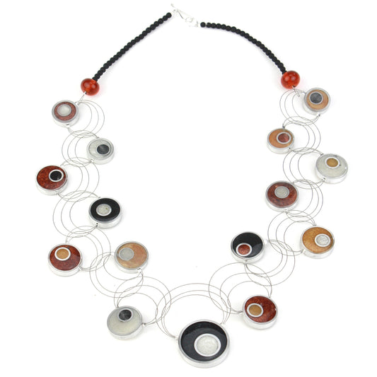 Resinique Interplay Necklace featuring intertwining steel cables with black, white, copper, and gold eco-resin circles and salvaged aluminum accents.