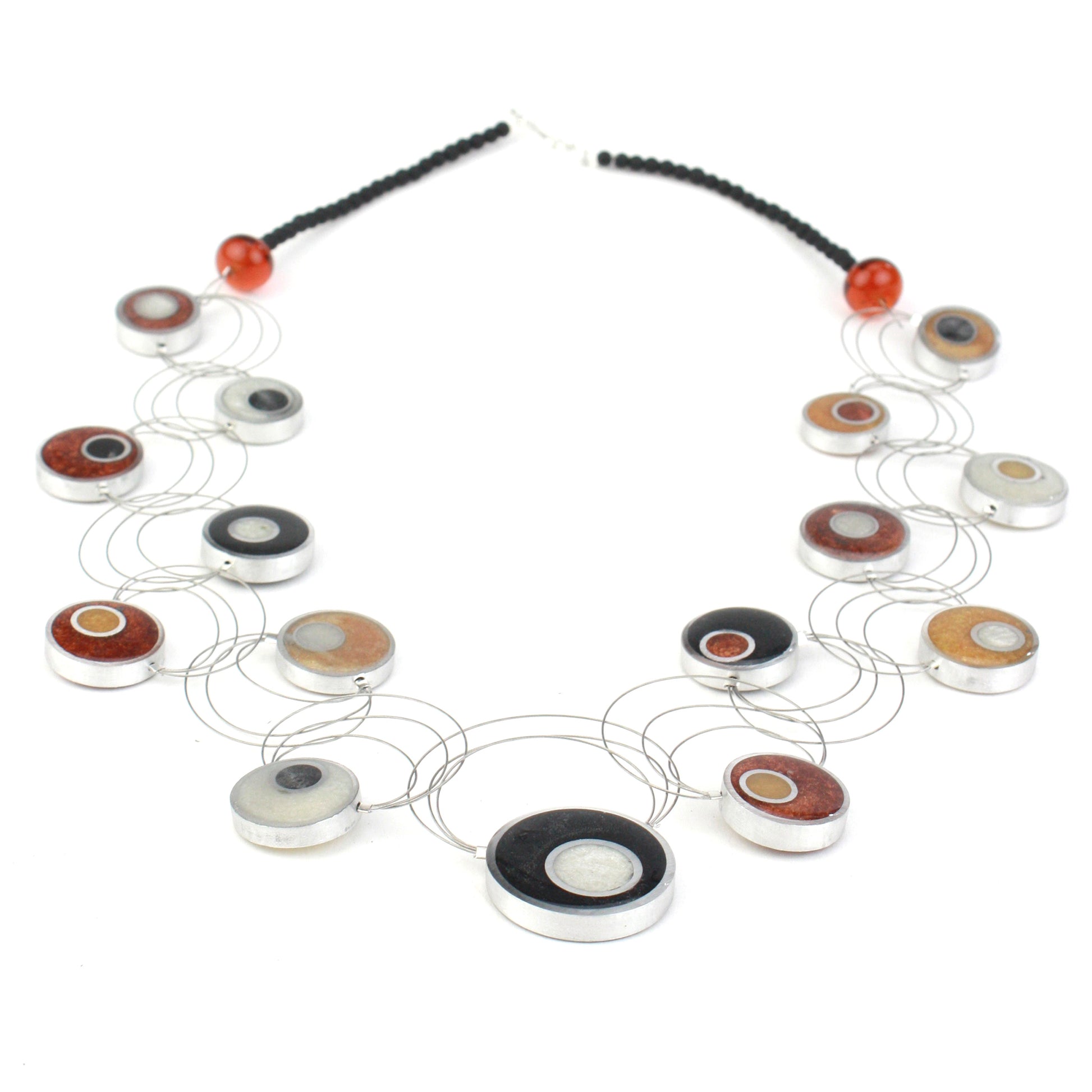 Resinique Interplay Necklace featuring intertwining steel cables with black, white, copper, and gold eco-resin circles and salvaged aluminum accents.