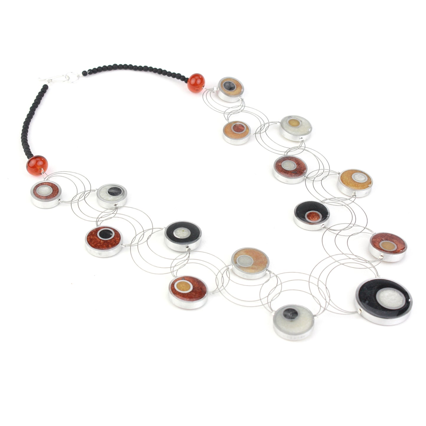 Resinique Interplay Necklace featuring intertwining steel cables with black, white, copper, and gold eco-resin circles and salvaged aluminum accents.