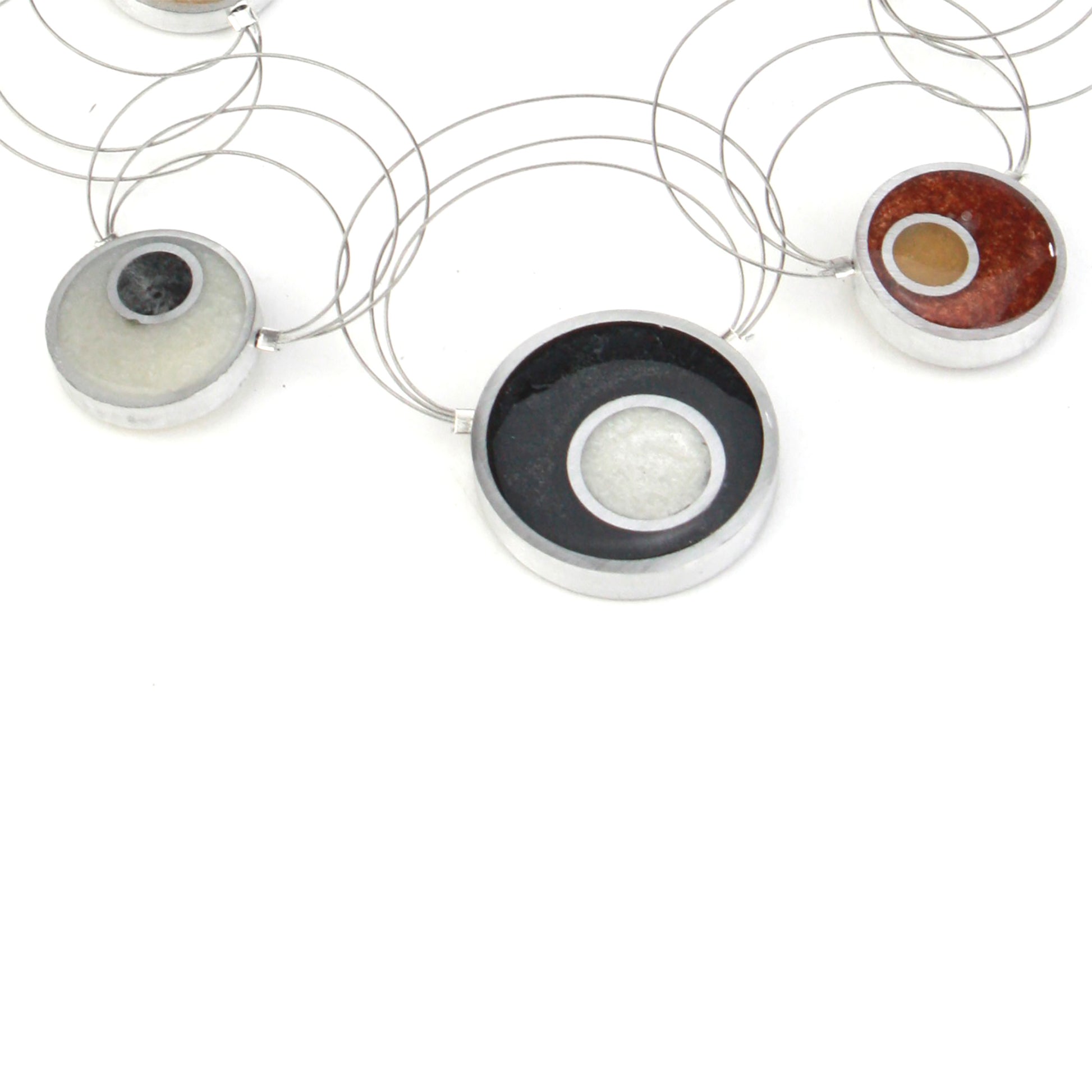 Resinique Interplay Necklace featuring intertwining steel cables with black, white, copper, and gold eco-resin circles and salvaged aluminum accents.