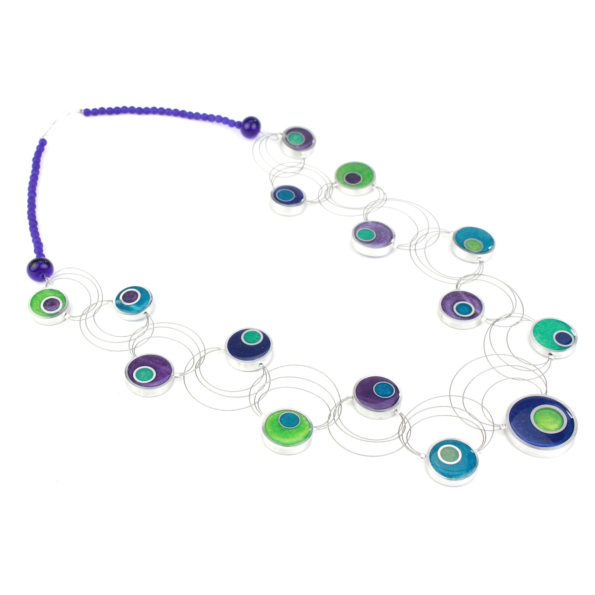 A handcrafted necklace featuring intertwining steel cables adorned with circular eco-resin and salvaged aluminum beads in shades of blue, green, and purple.