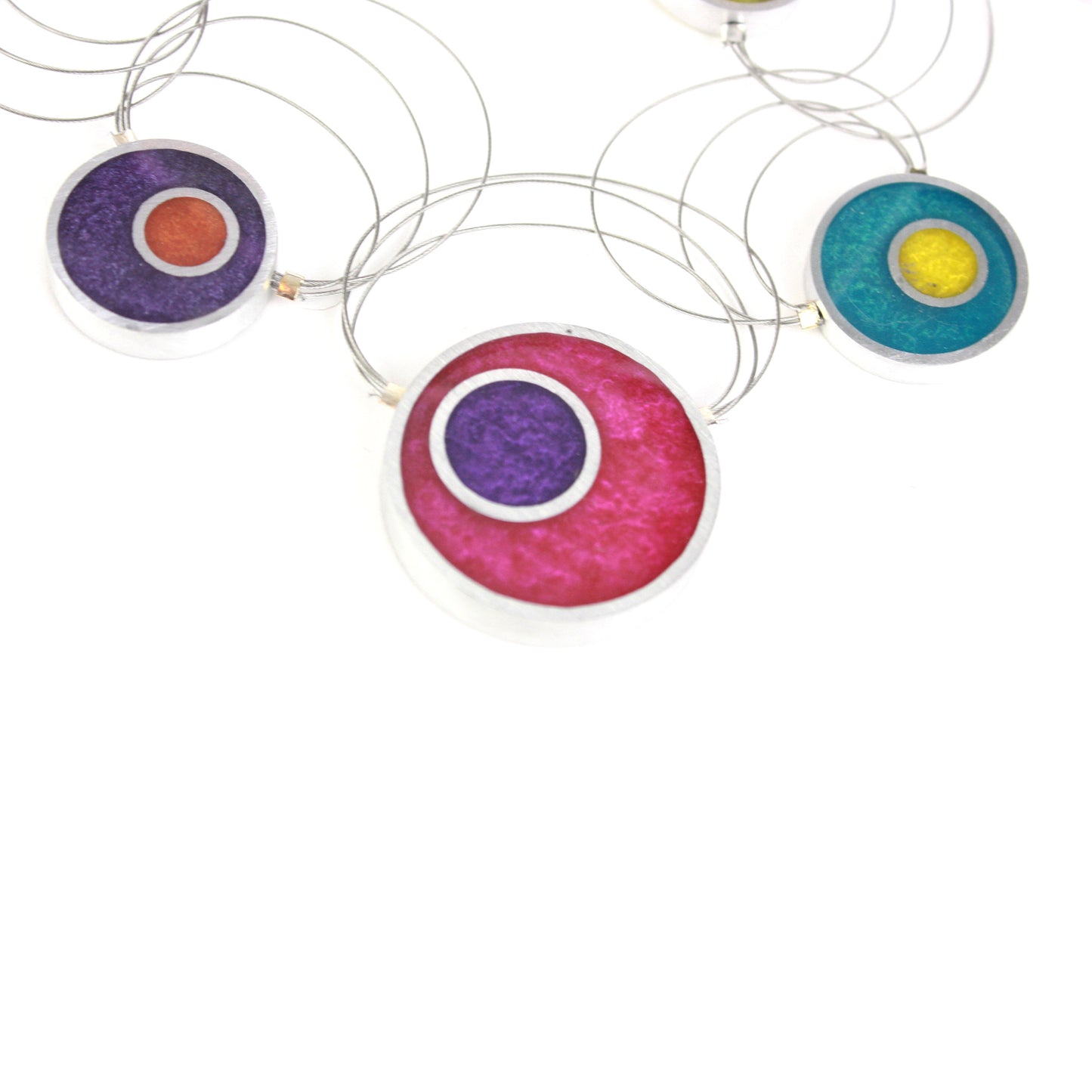 A handcrafted necklace with intertwining steel cables featuring multi-colored eco-resin and salvaged aluminum beads in vibrant shades of red, purple, green, blue, and orange.