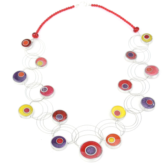 A handcrafted necklace featuring intertwining steel cables with eco-resin and salvaged aluminum beads in warm shades of red, orange, yellow, and purple.