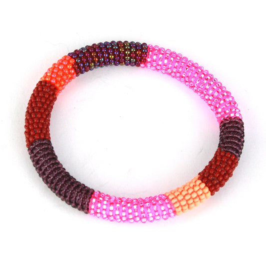 A bold bangle bracelet featuring tiny glass beads in shades of pink, red, maroon, and orange, wrapped around a flexible silicone core for effortless wear.