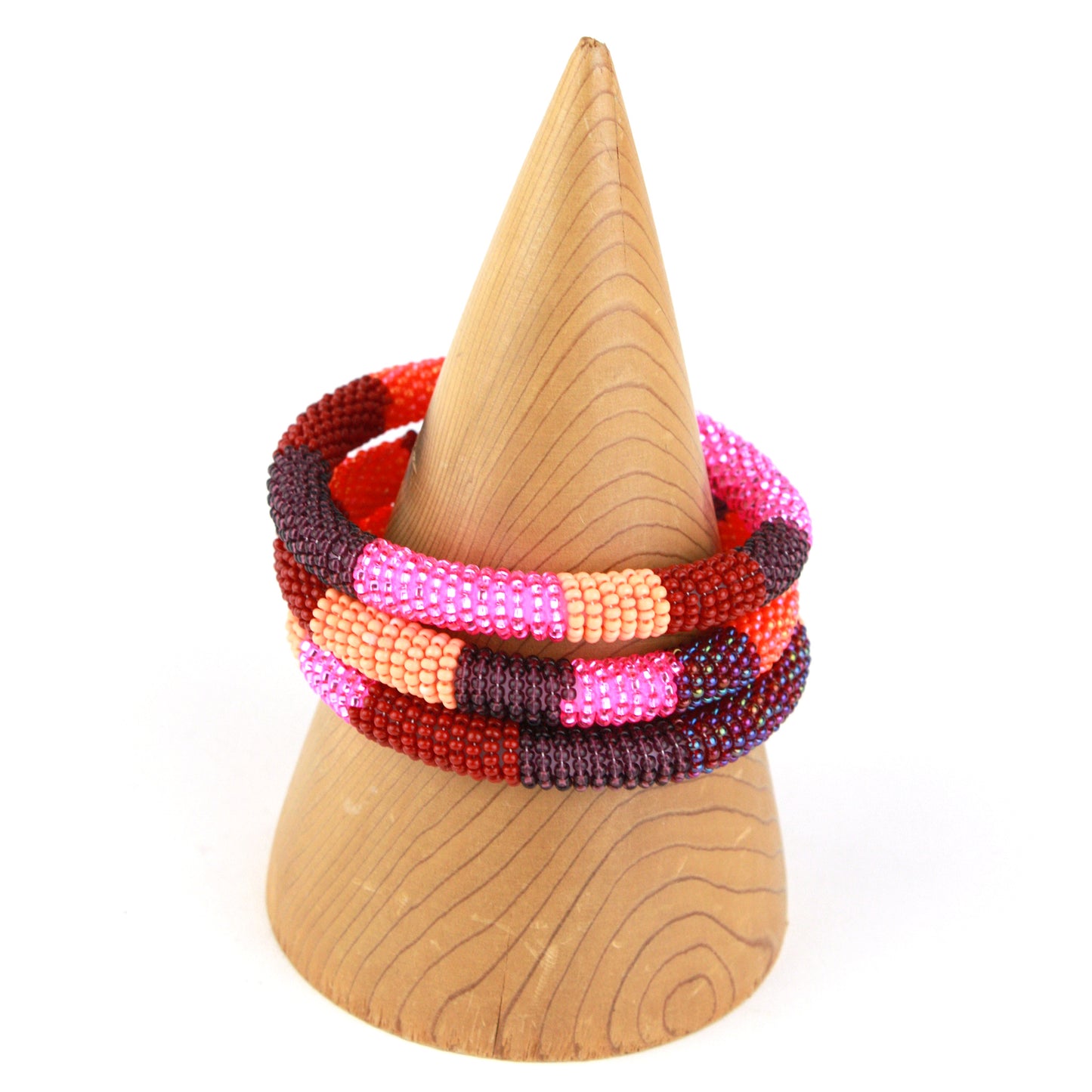 A bold bangle bracelet featuring tiny glass beads in shades of pink, red, maroon, and orange, wrapped around a flexible silicone core for effortless wear.
