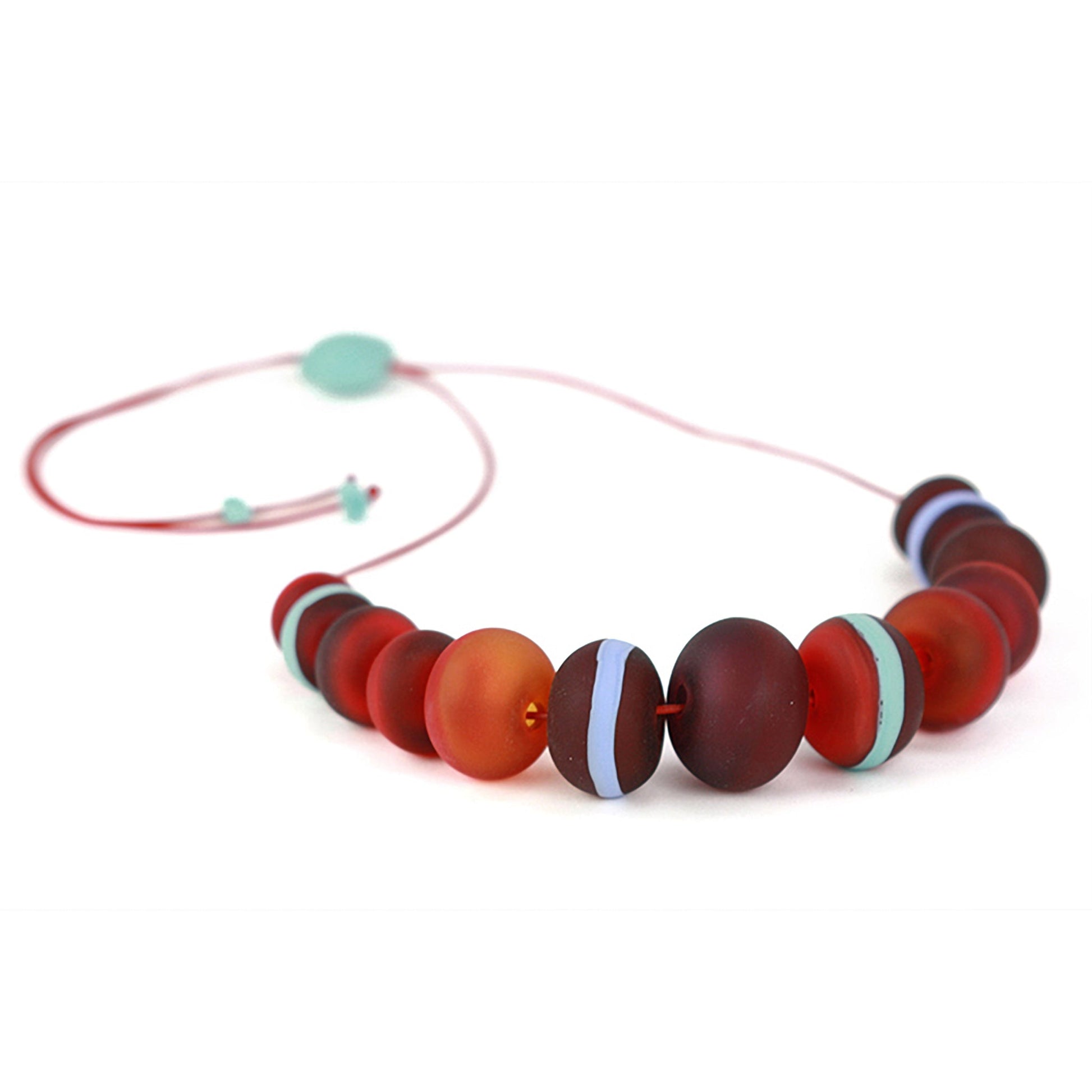 Soft Stripes Necklace with hand-blown sandblasted glass beads in red, orange, and blue hues, strung on an adjustable fine leather cord.