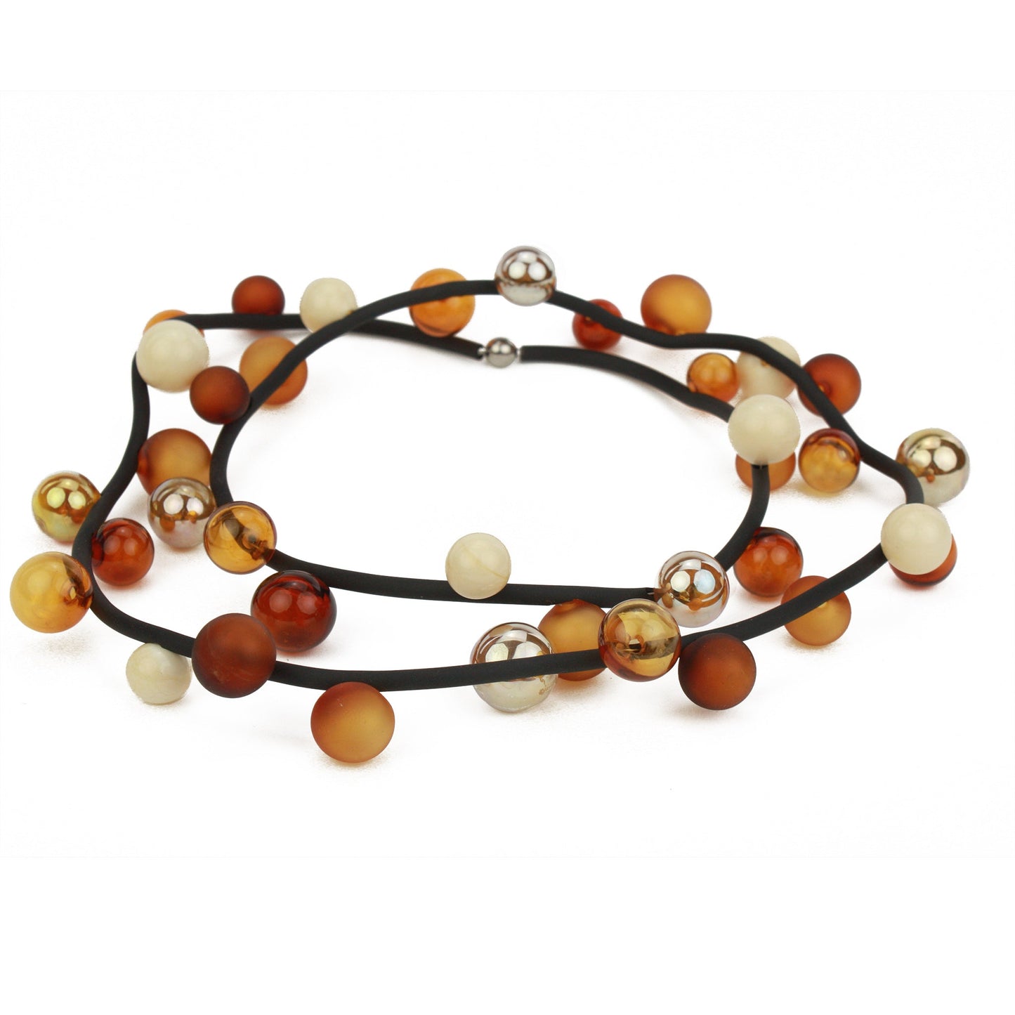 The "Bolla" necklace featuring hand-blown glass beads in amber, gold, and cream tones, strung on a steel cable through a rubber cord, worn long or doubled up.