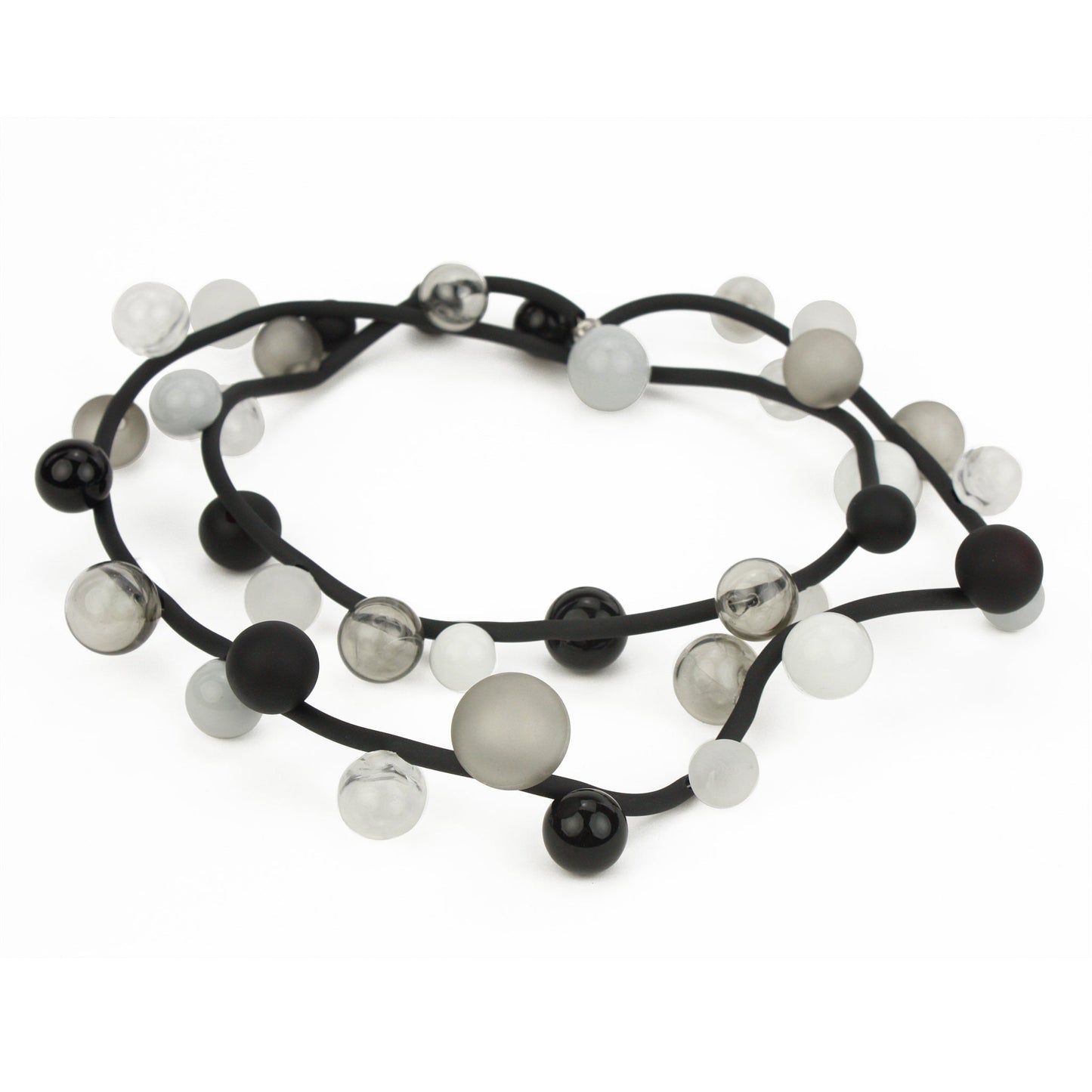 "Bolla" necklace featuring monochrome hand-blown glass beads in black, white, and clear shades, strung on a steel cable with a rubber cord, worn long or doubled.