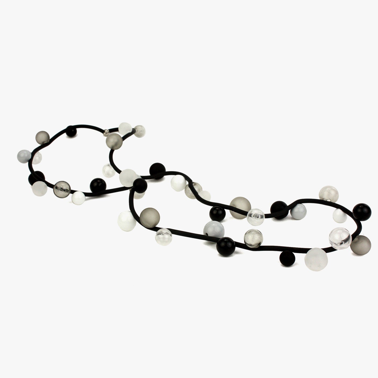 "Bolla" necklace featuring monochrome hand-blown glass beads in black, white, and clear shades, strung on a steel cable with a rubber cord, worn long or doubled.