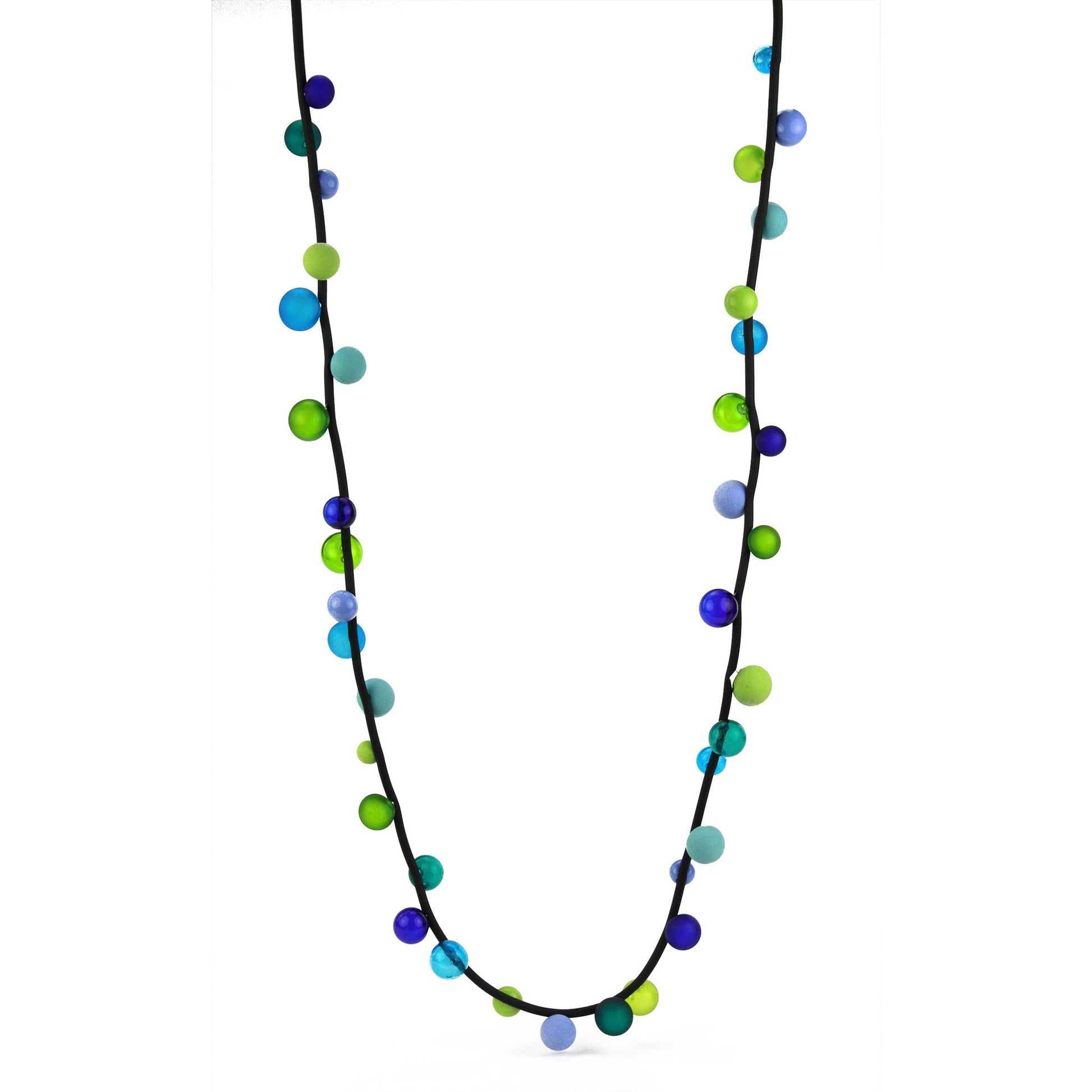 The "Bolla" necklace featuring hand-blown glass beads in shades of blue, green, and teal, strung on a steel cable threaded through a rubber cord, worn long or doubled.