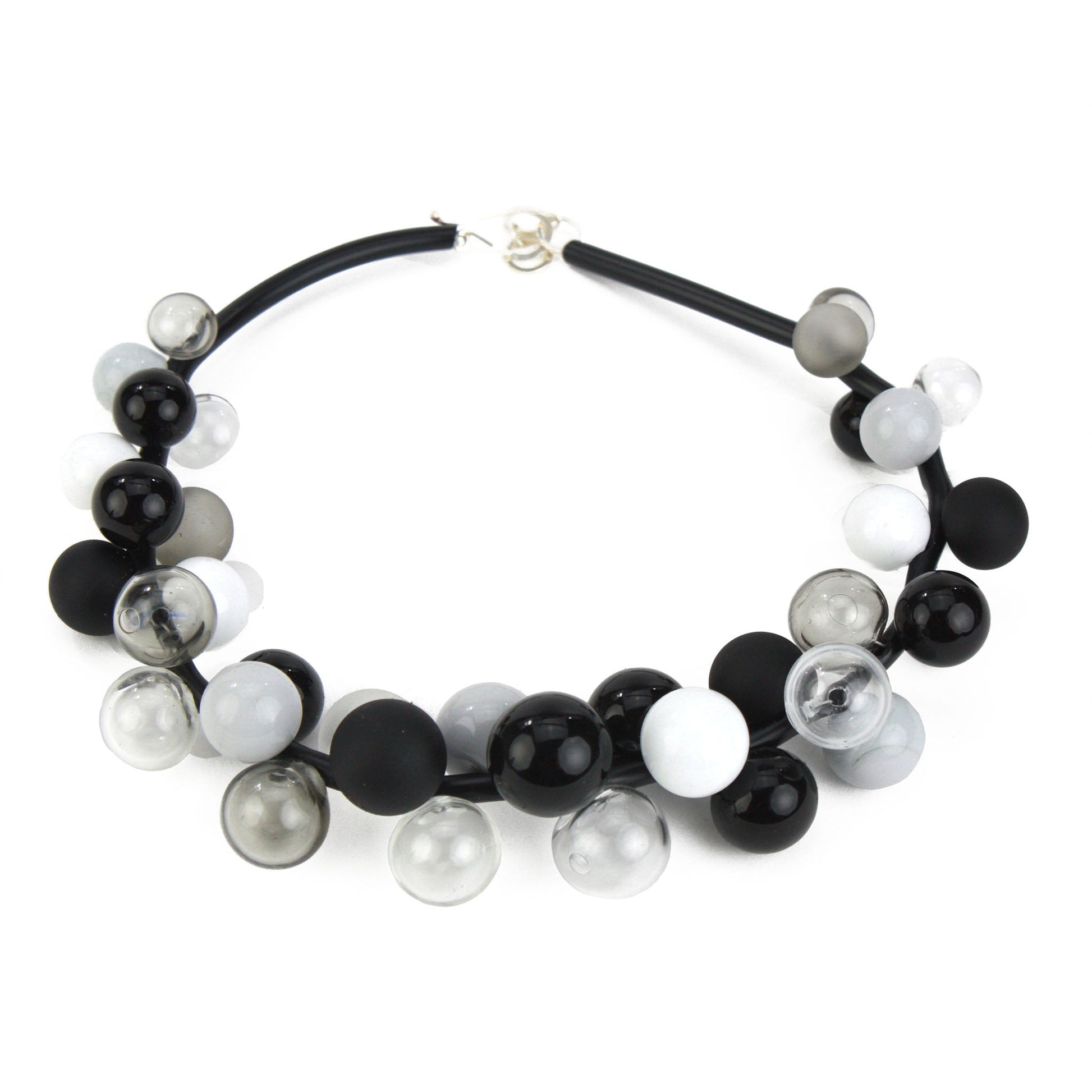 A sophisticated "Bolla" necklace featuring hand-blown glass beads in black, white, and grey tones, strung on steel cable through a rubber cord with a sterling silver clasp.