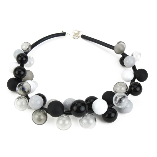 A sophisticated "Bolla" necklace featuring hand-blown glass beads in black, white, and grey tones, strung on steel cable through a rubber cord with a sterling silver clasp.
