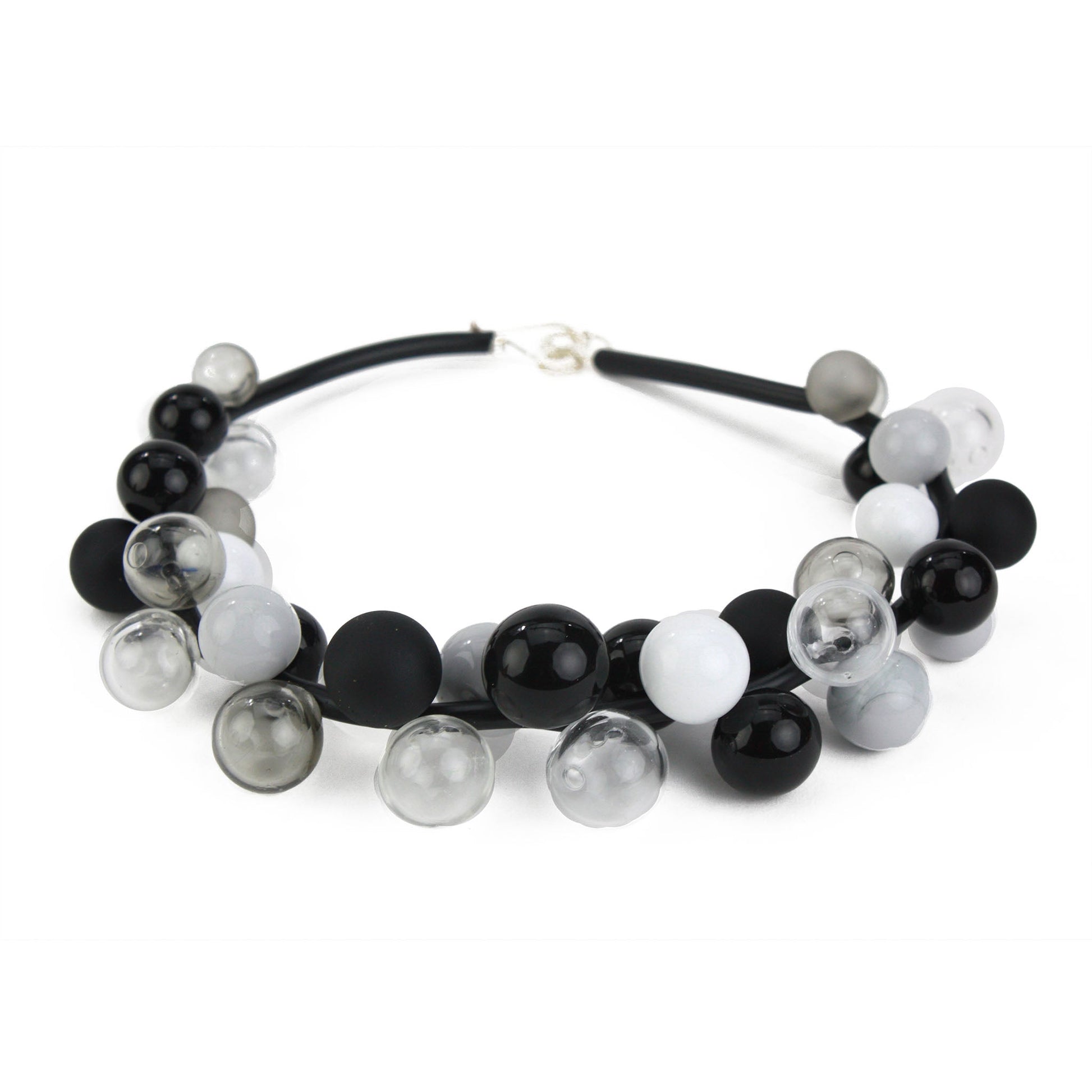 A sophisticated "Bolla" necklace featuring hand-blown glass beads in black, white, and grey tones, strung on steel cable through a rubber cord with a sterling silver clasp.