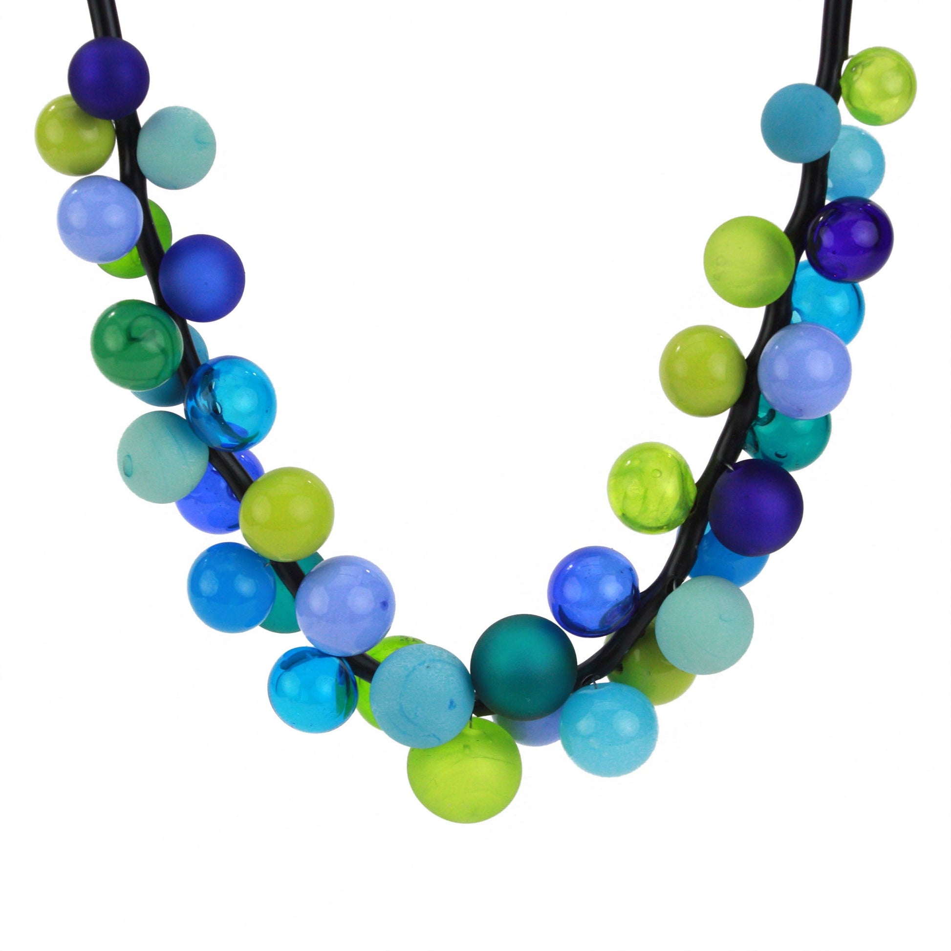 The "Bolla" necklace featuring hand-blown glass beads in shades of blue, green, and teal, strung on a steel cable threaded through a rubber cord with a sterling silver clasp.