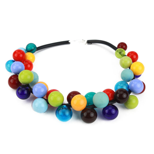The "Bolla" necklace featuring vibrant hand-blown glass beads in rainbow hues, strung on steel cable through a rubber cord with a sterling silver clasp.