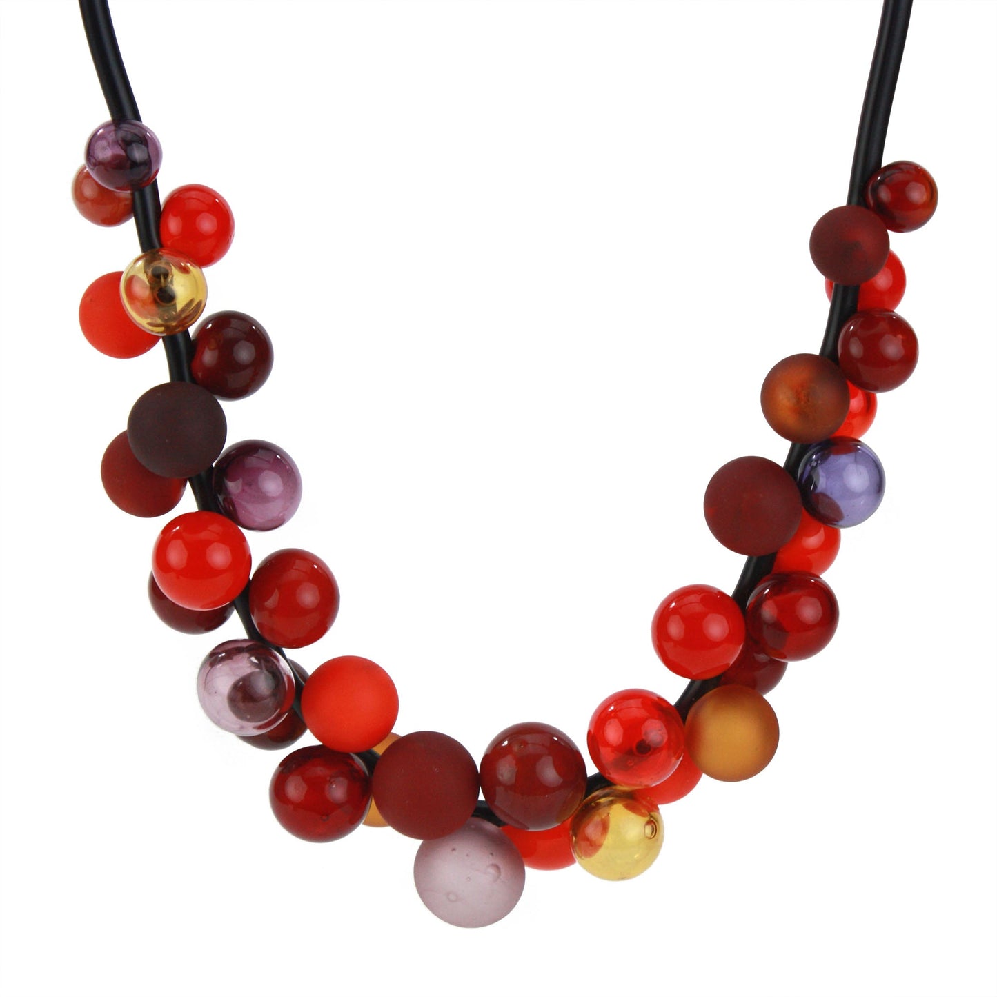 The "Bolla" necklace featuring hand-blown glass beads in shades of red, maroon, and amber, strung on a steel cable threaded through a rubber cord with a sterling silver clasp.