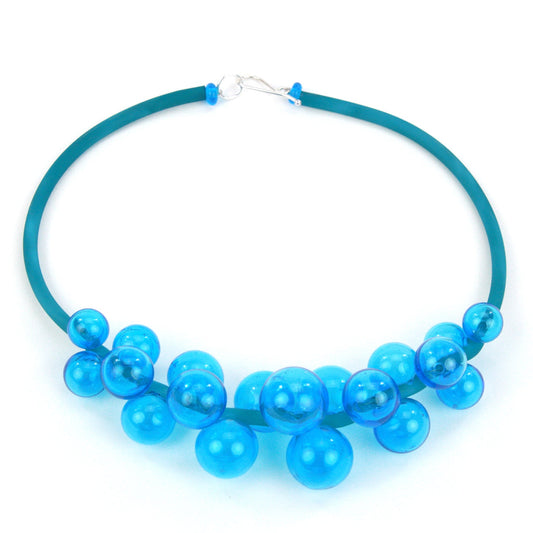A vibrant aqua Chroma necklace featuring a cluster of handmade glass beads strung on steel and threaded through a hand-dyed silicone cord with a sterling silver clasp.