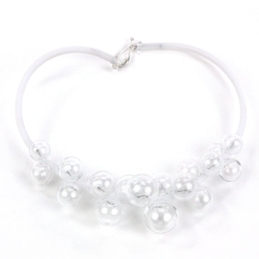A clear Chroma necklace featuring transparent glass beads clustered on steel wire and threaded through a white hand-dyed silicone cord with a sterling silver clasp.