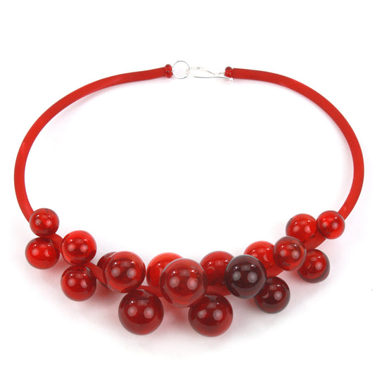 A bold red Chroma necklace featuring clusters of handblown glass beads strung on steel wire and a hand-dyed silicone cord with a sterling silver clasp.