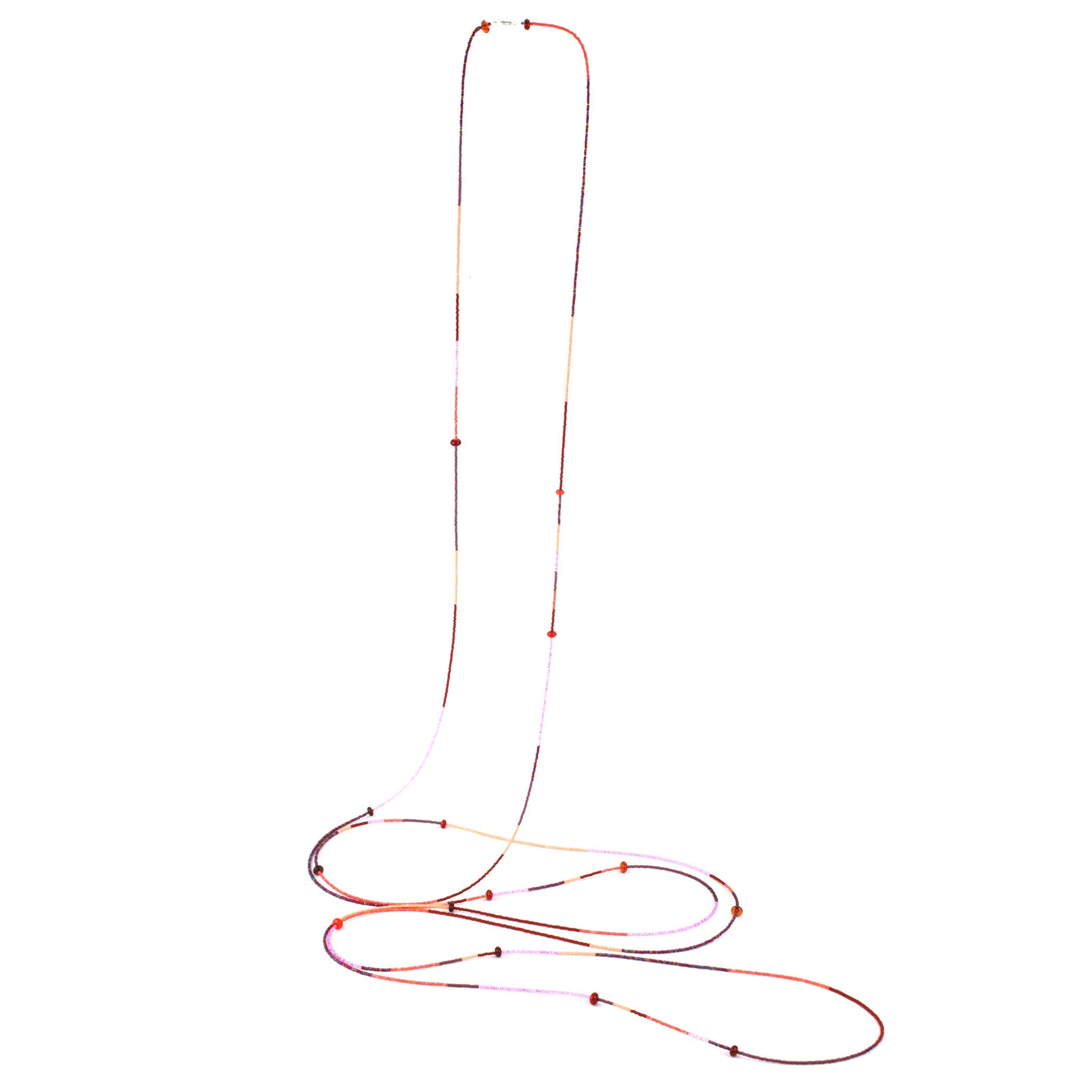 A 12-foot necklace featuring tiny glass seed beads in warm shades of red, orange, and pink, accented with handcrafted lampworked beads. The necklace includes a secure barrel screw clasp and can be styled as a layered necklace or wrapped around the wrist as a bracelet.