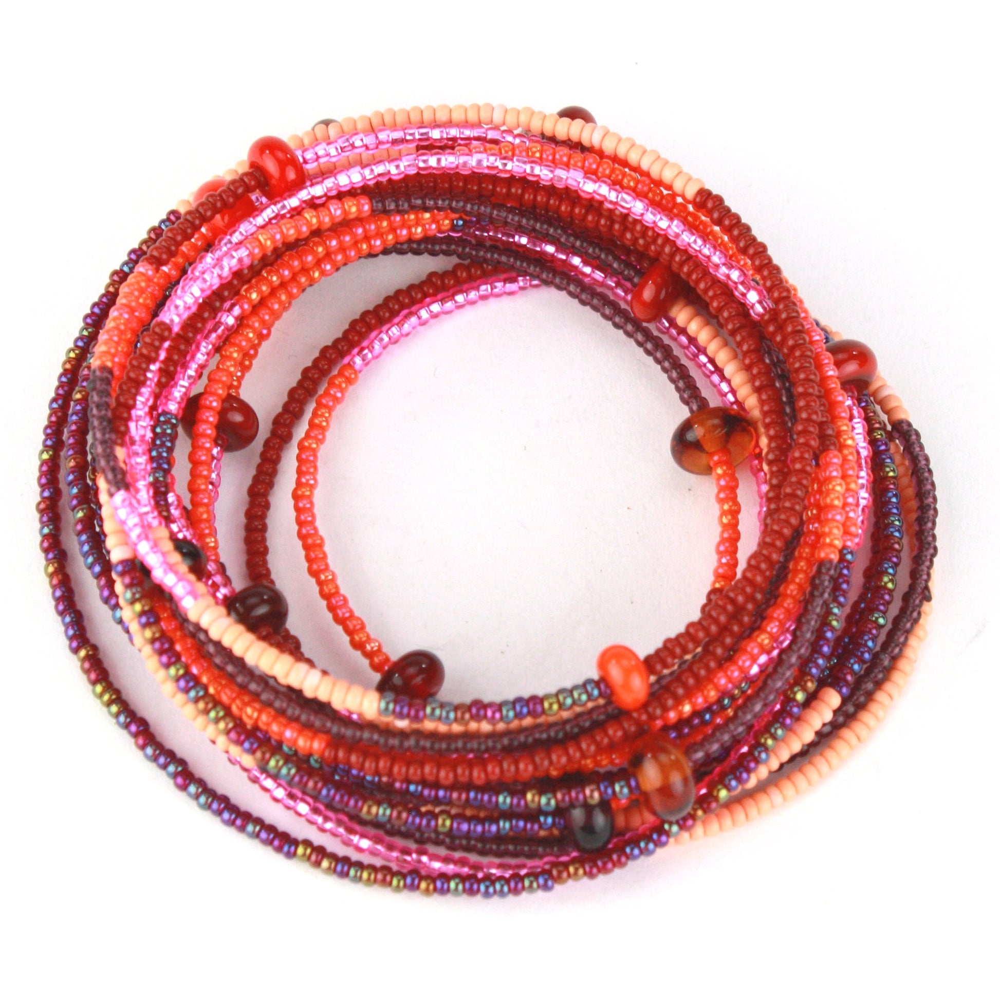 A 12-foot necklace featuring tiny glass seed beads in warm shades of red, orange, and pink, accented with handcrafted lampworked beads. The necklace includes a secure barrel screw clasp and can be styled as a layered necklace or wrapped around the wrist as a bracelet.